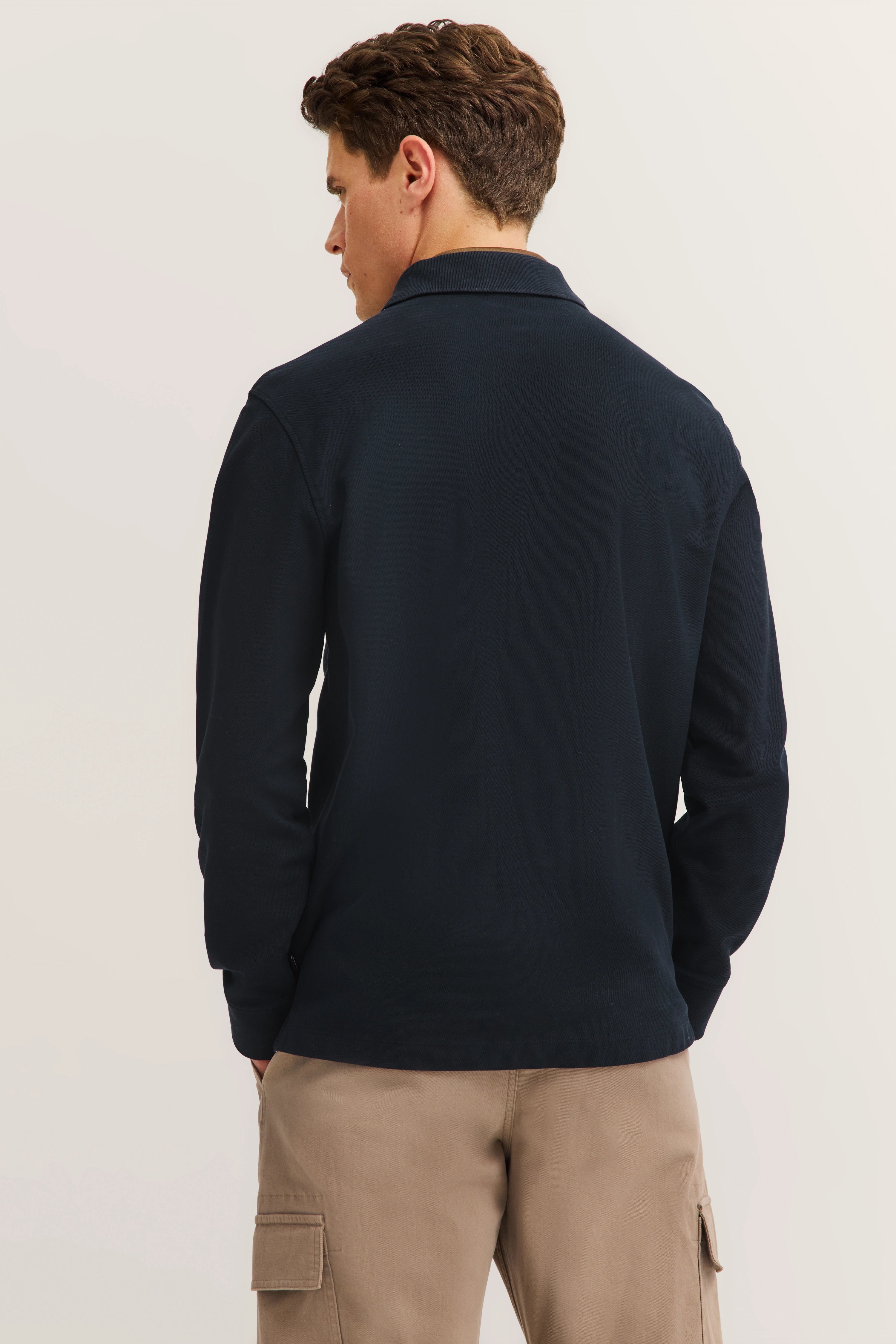 Model in dunkelblauem bugatti Langarmshirt, beige Cargo-Hose, Rückansicht, legeres Posing.