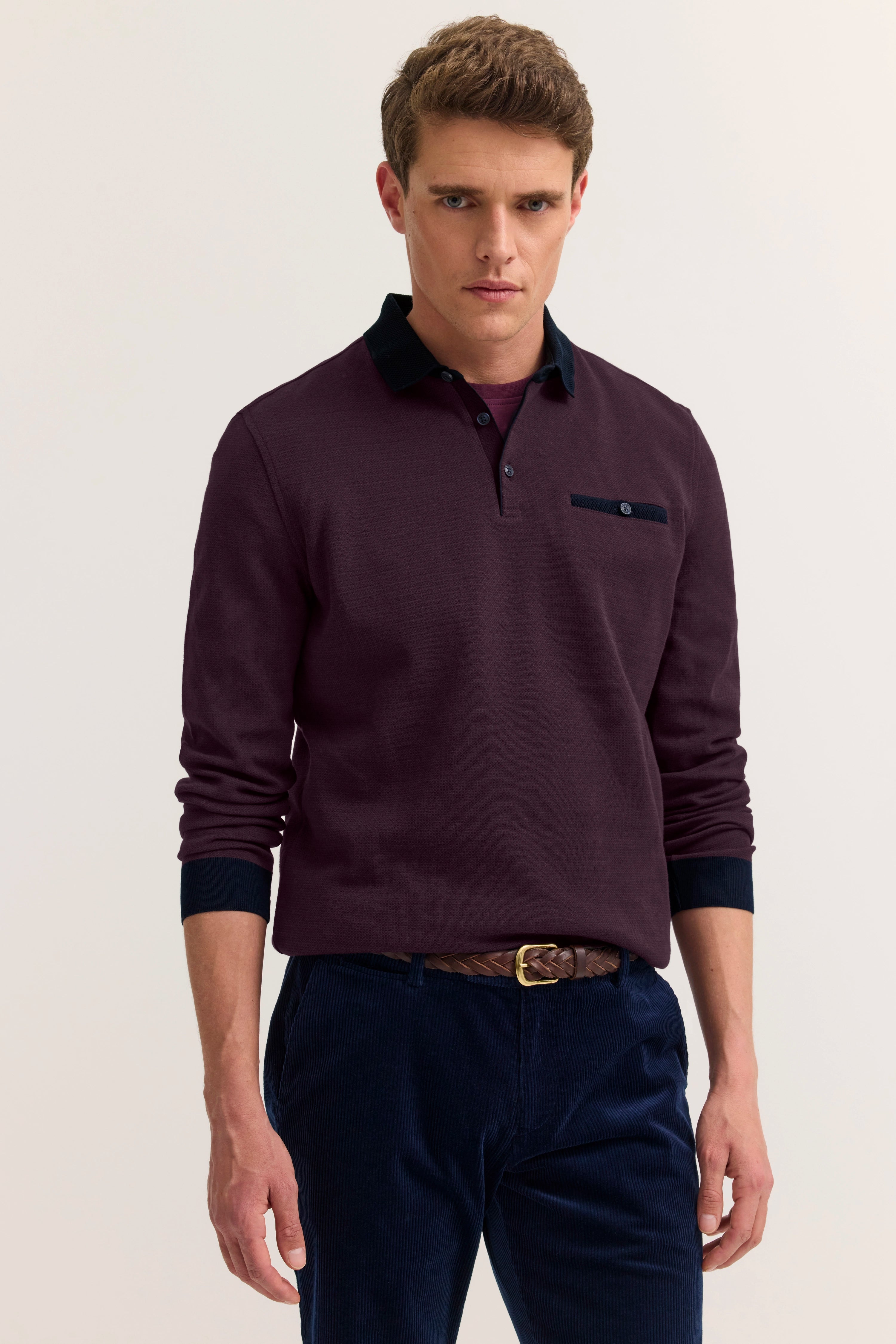 Model in bordeaux bugatti-Pullover, schwarzem Kragen, marine Hose, lässige Pose.