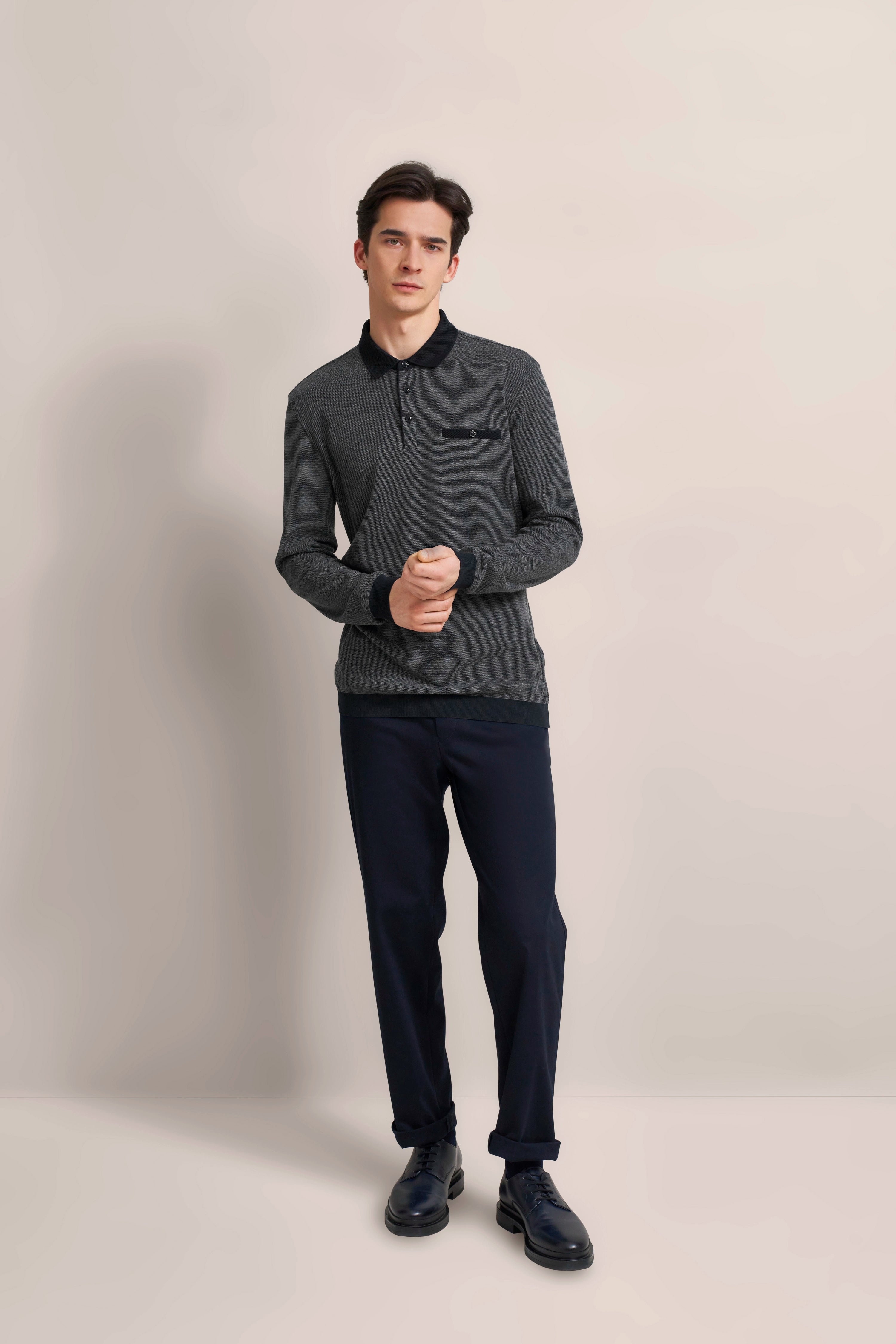 bugatti model in gray polo shirt and blue pants, casual pose with crossed hands.