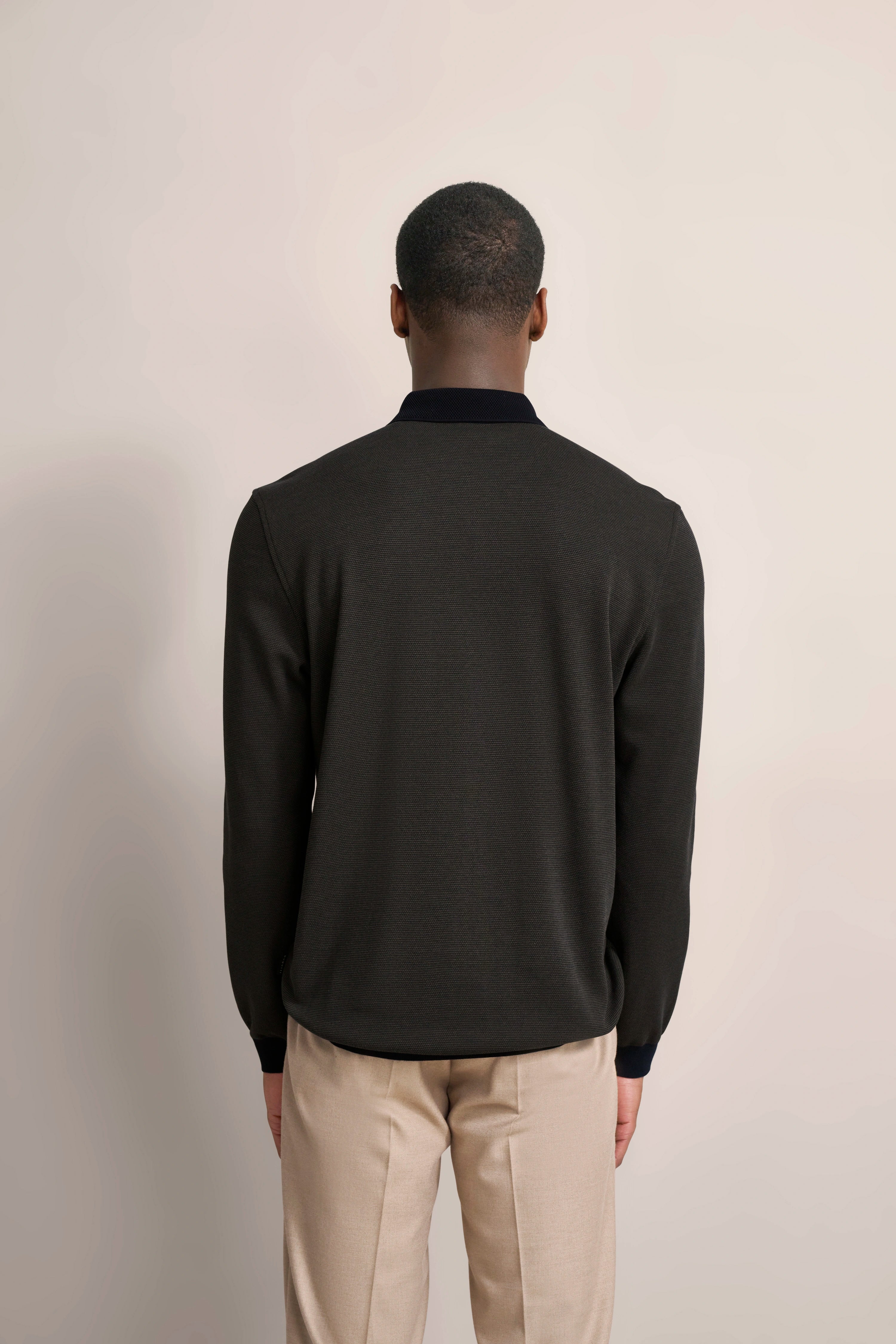Schwarzer Pullover und beige Hose Rückansicht, Modelbild mit aufrechtem Posing, bugatti Stil.