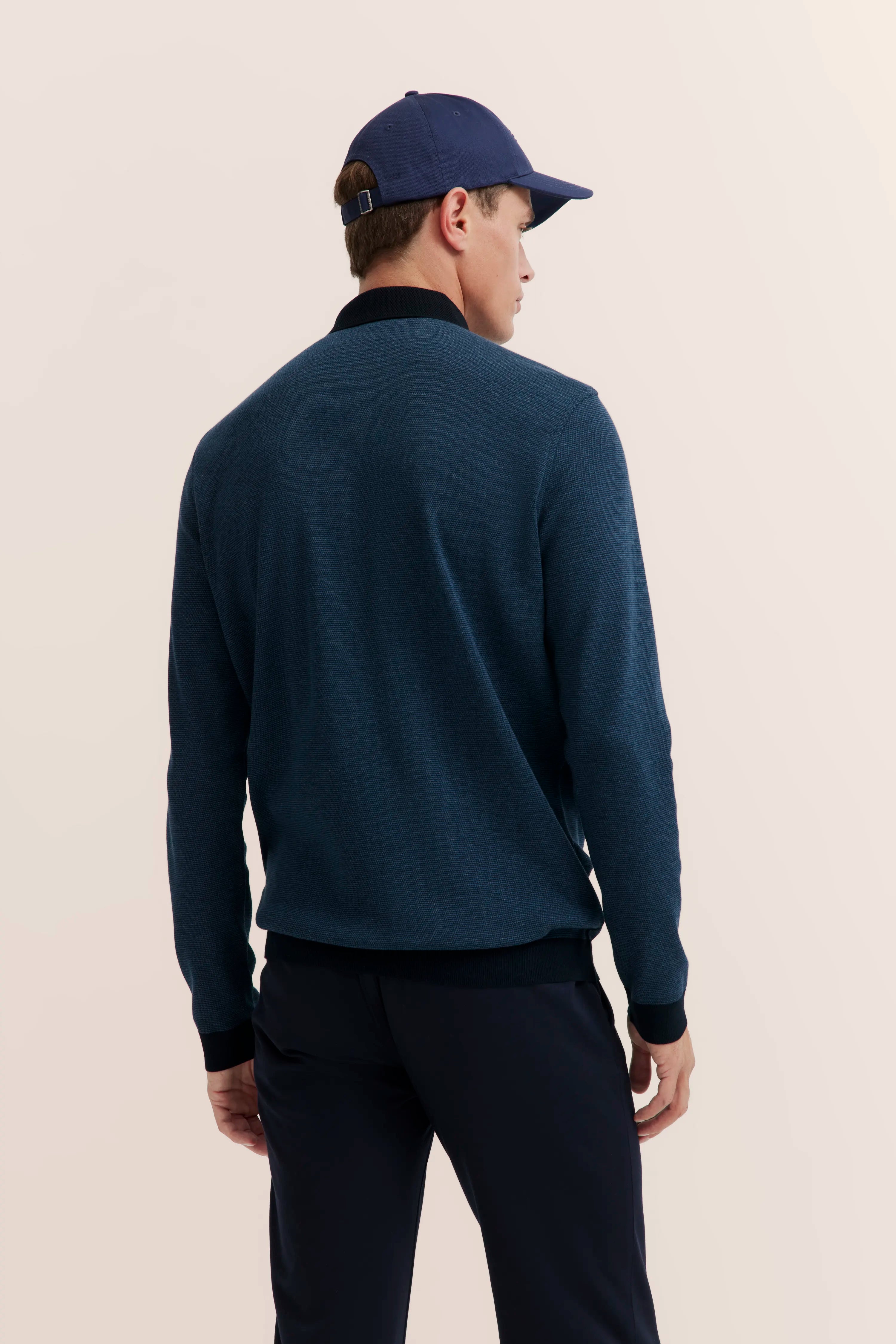 Dark blue sweater and cap, side model view from behind, casual style.