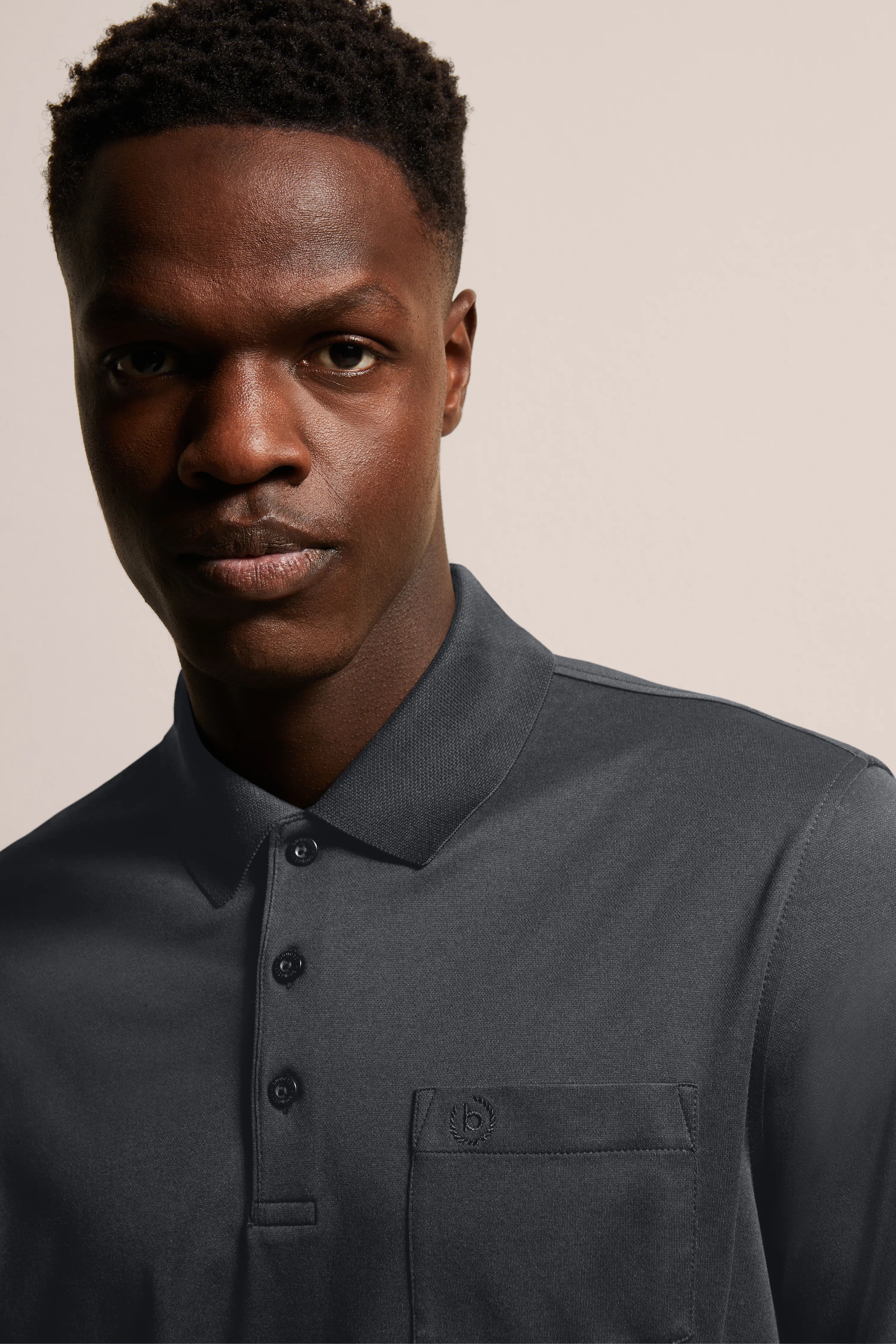 Borstbeeld van een man in donkergrijs bugatti poloshirt, elegante look met knoopsluiting en borstzak.