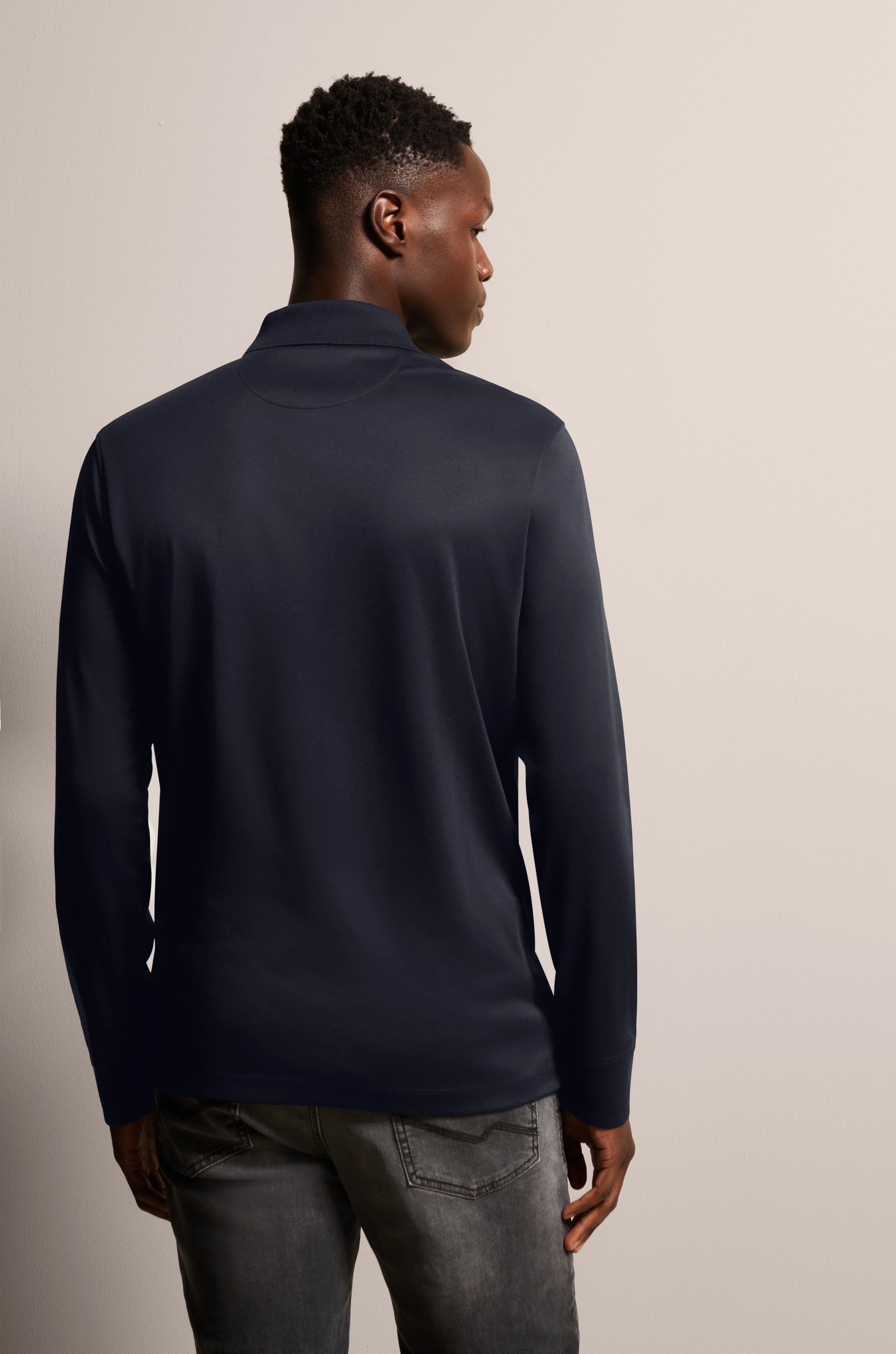 Donkerblauwe bugatti trui, model van achteren, casual in grijze jeans.