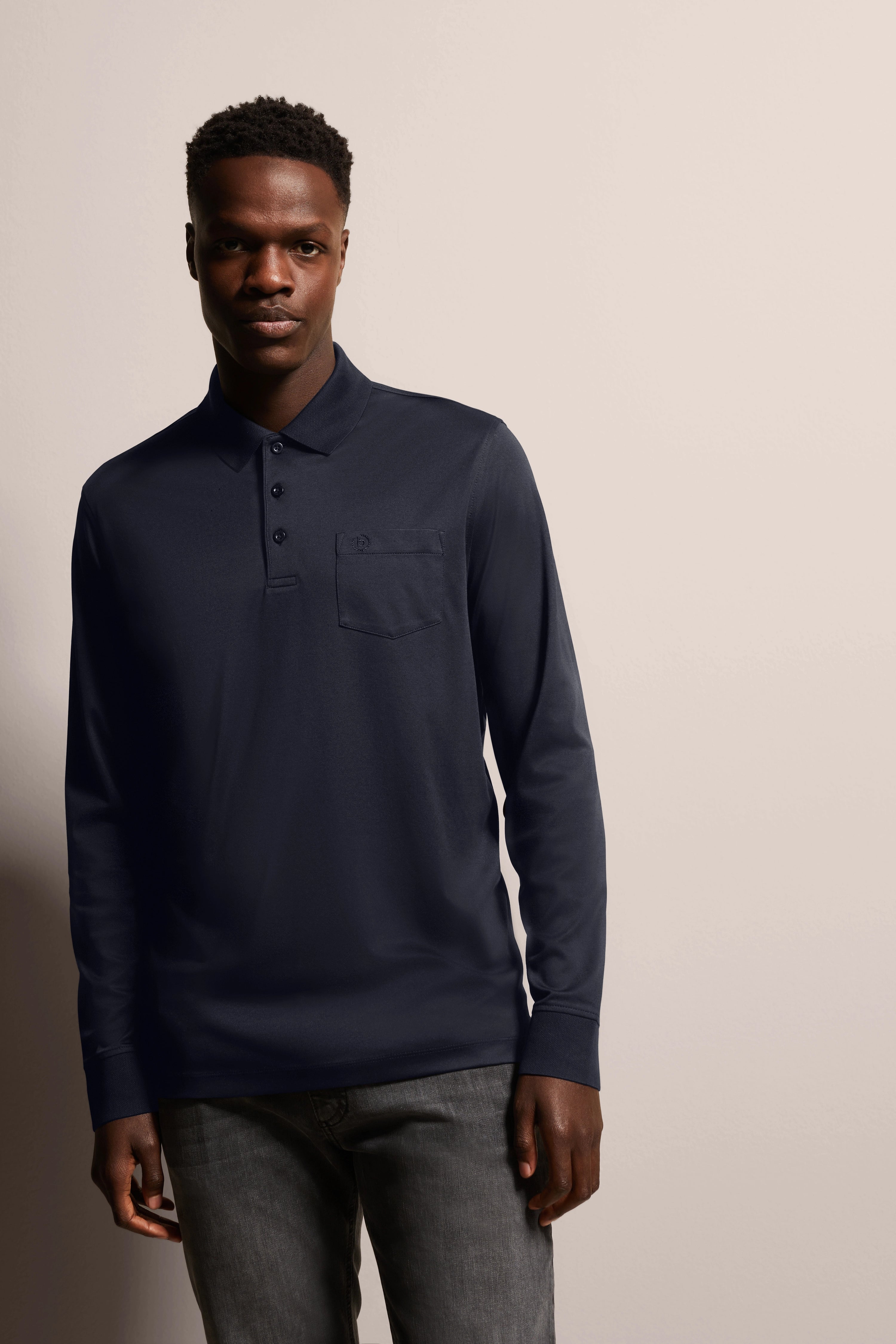 Model in dark blue bugatti polo, casual pose, paired with gray jeans.