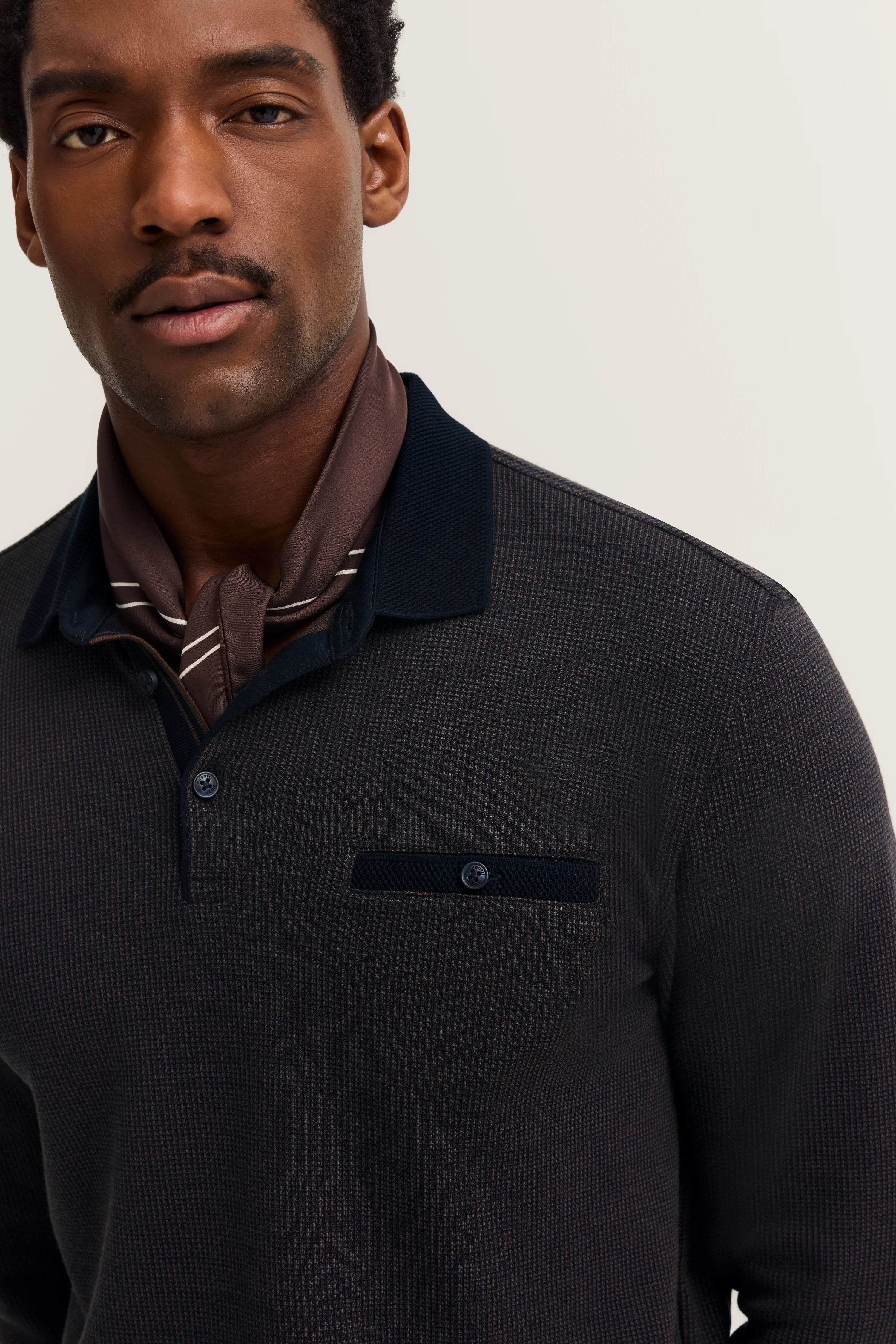 Model in bugatti polo, dark melange, with brown scarf, casual pose.