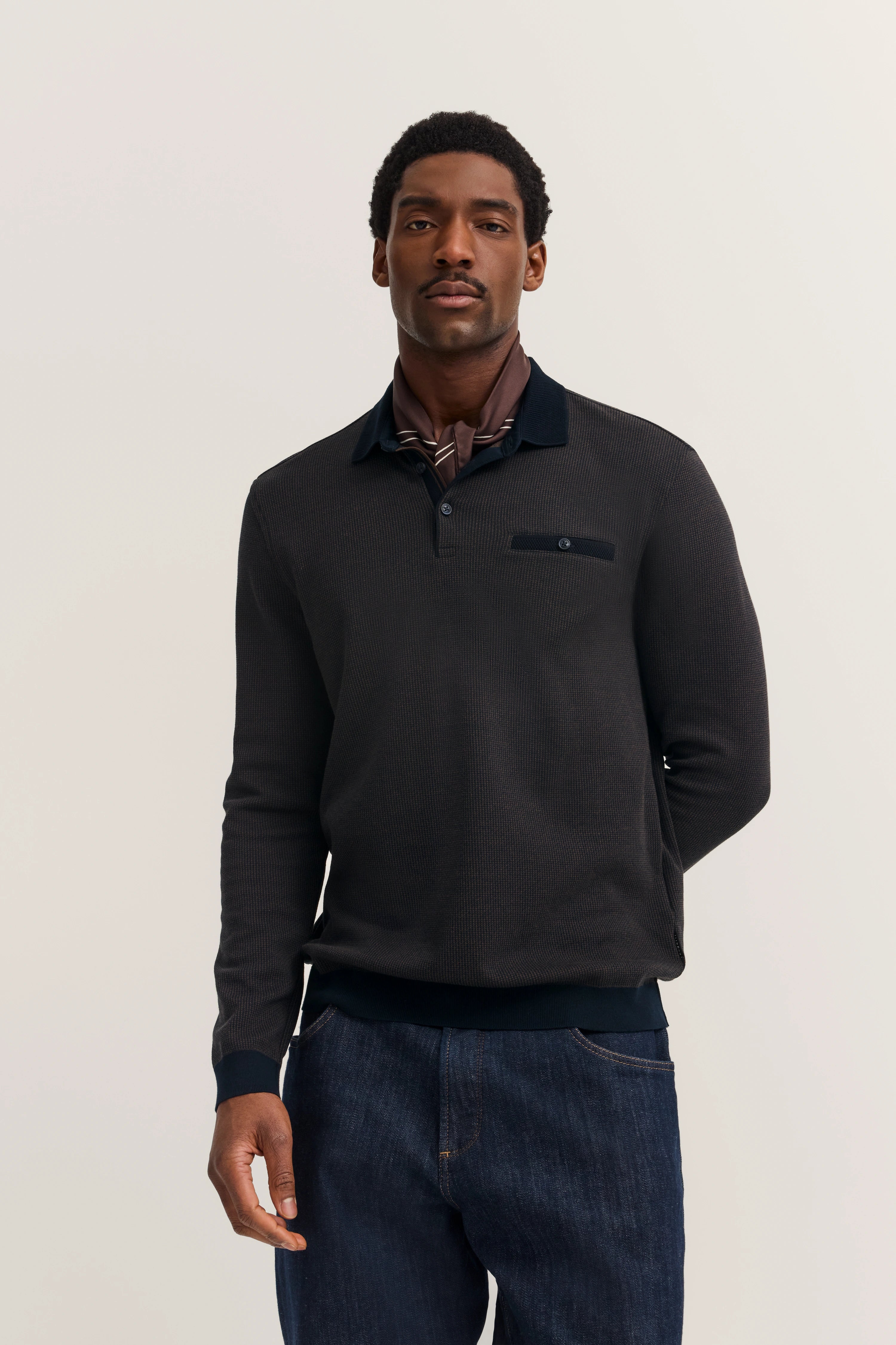 bugatti model: man in black sweater and jeans, relaxed pose, exuding timeless style and Italian elegance.