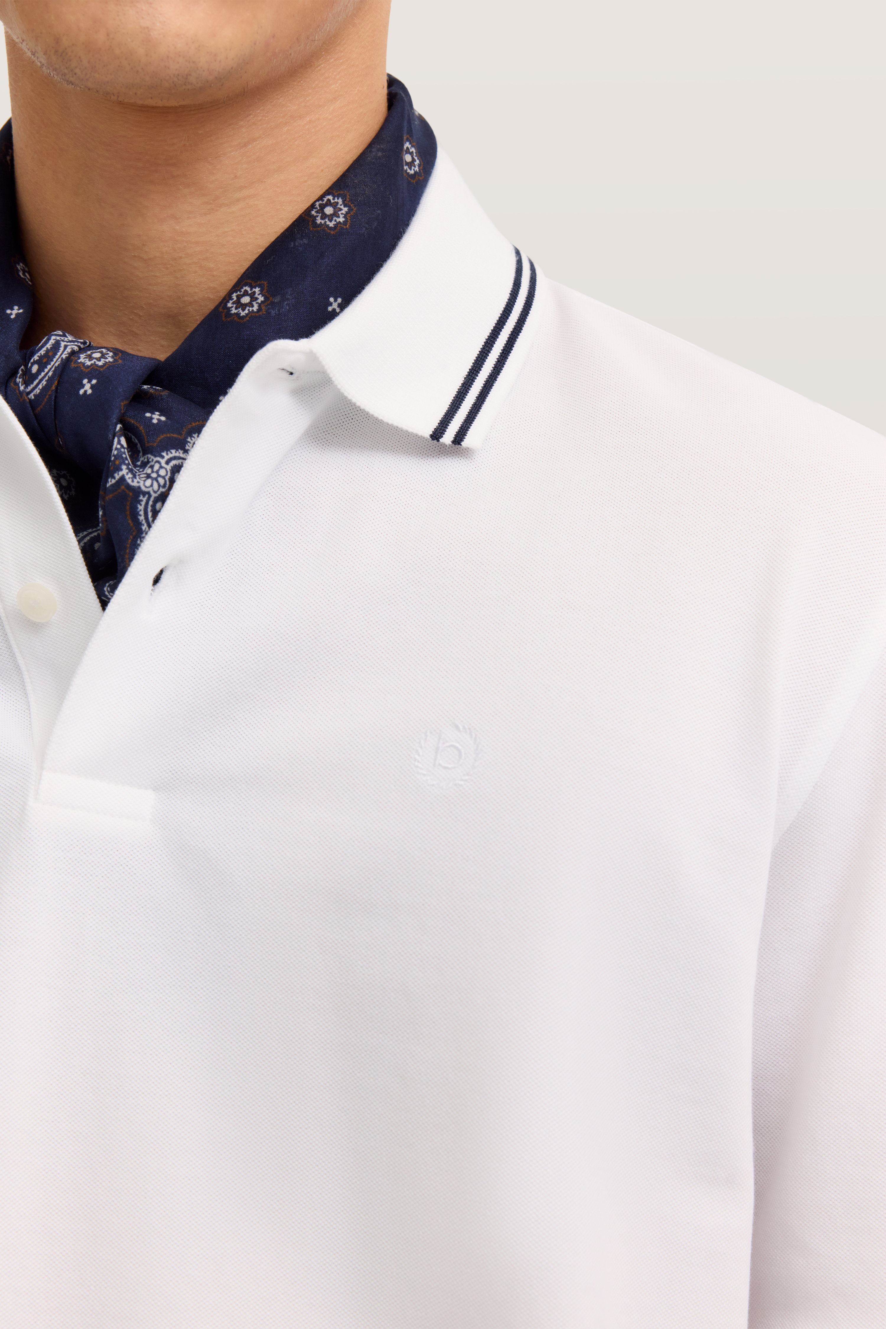 Weißes bugatti Polo mit dunkelblauem Muster-Schal, Detailansicht.
