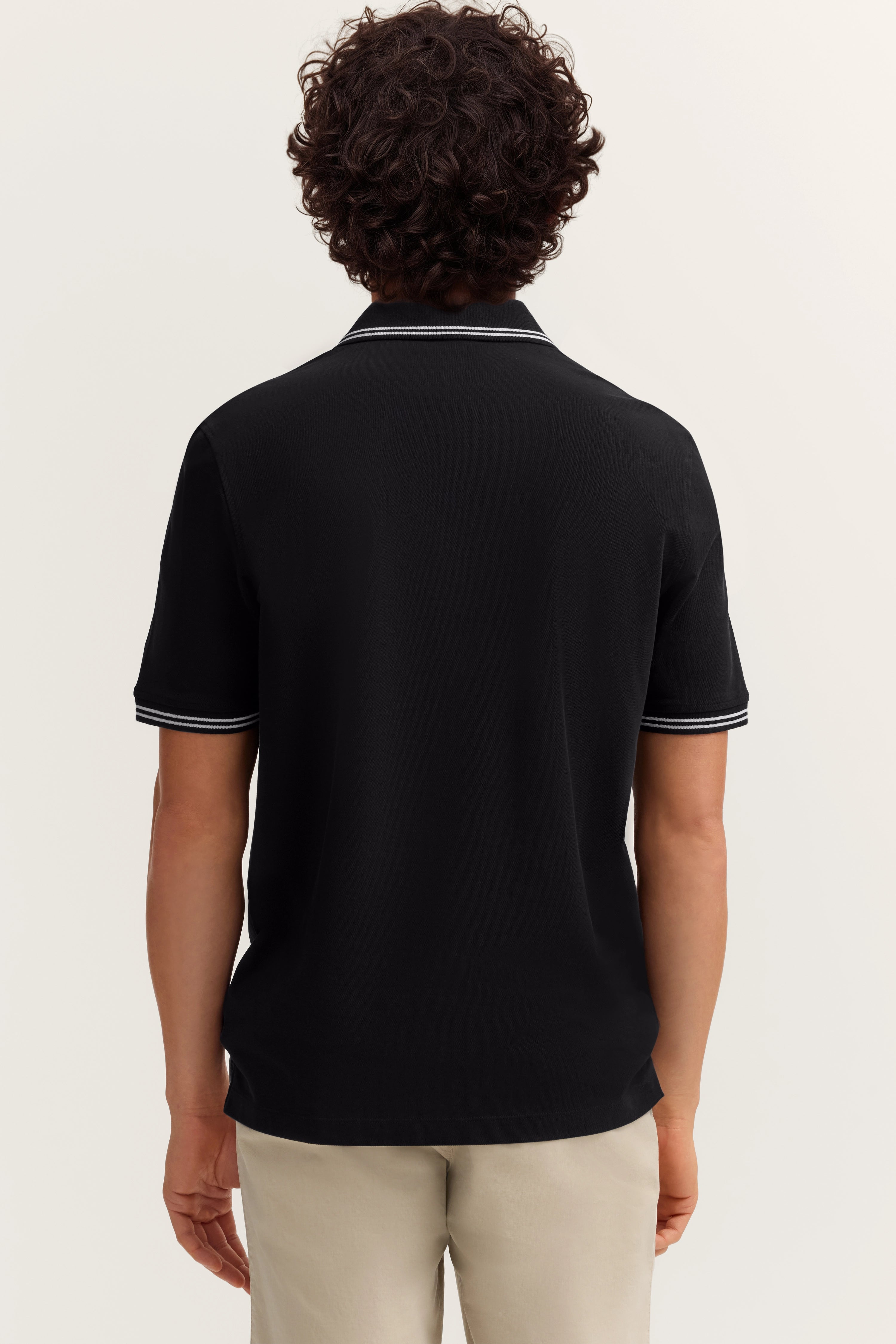 Schwarzes Poloshirt von bugatti, Rückansicht, mit grauem Kragenstreifen, leger getragen.