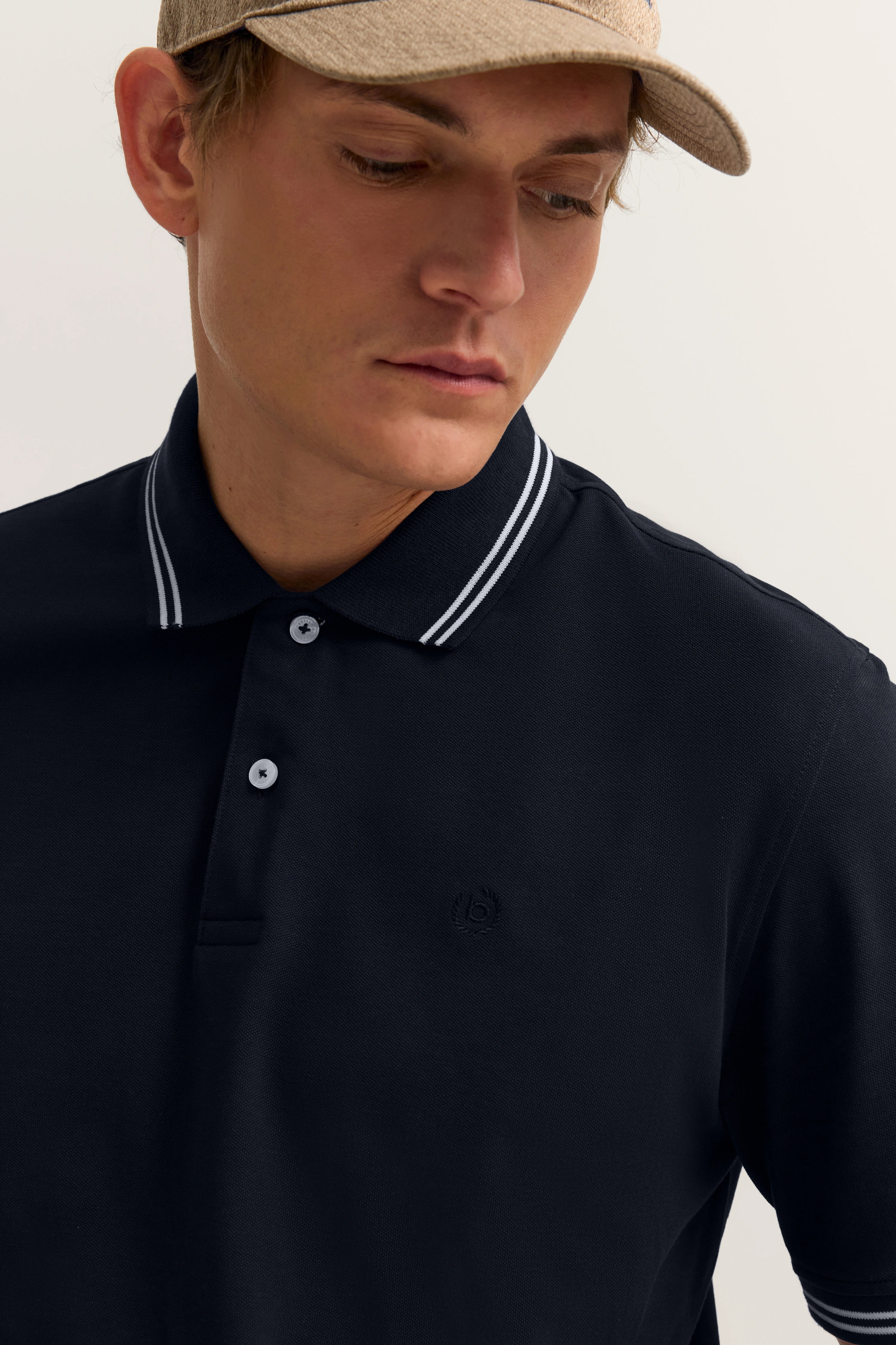 Model in navy Polo-Shirt von bugatti, legeres Bild, beige Kappe, entspanntes Posing.