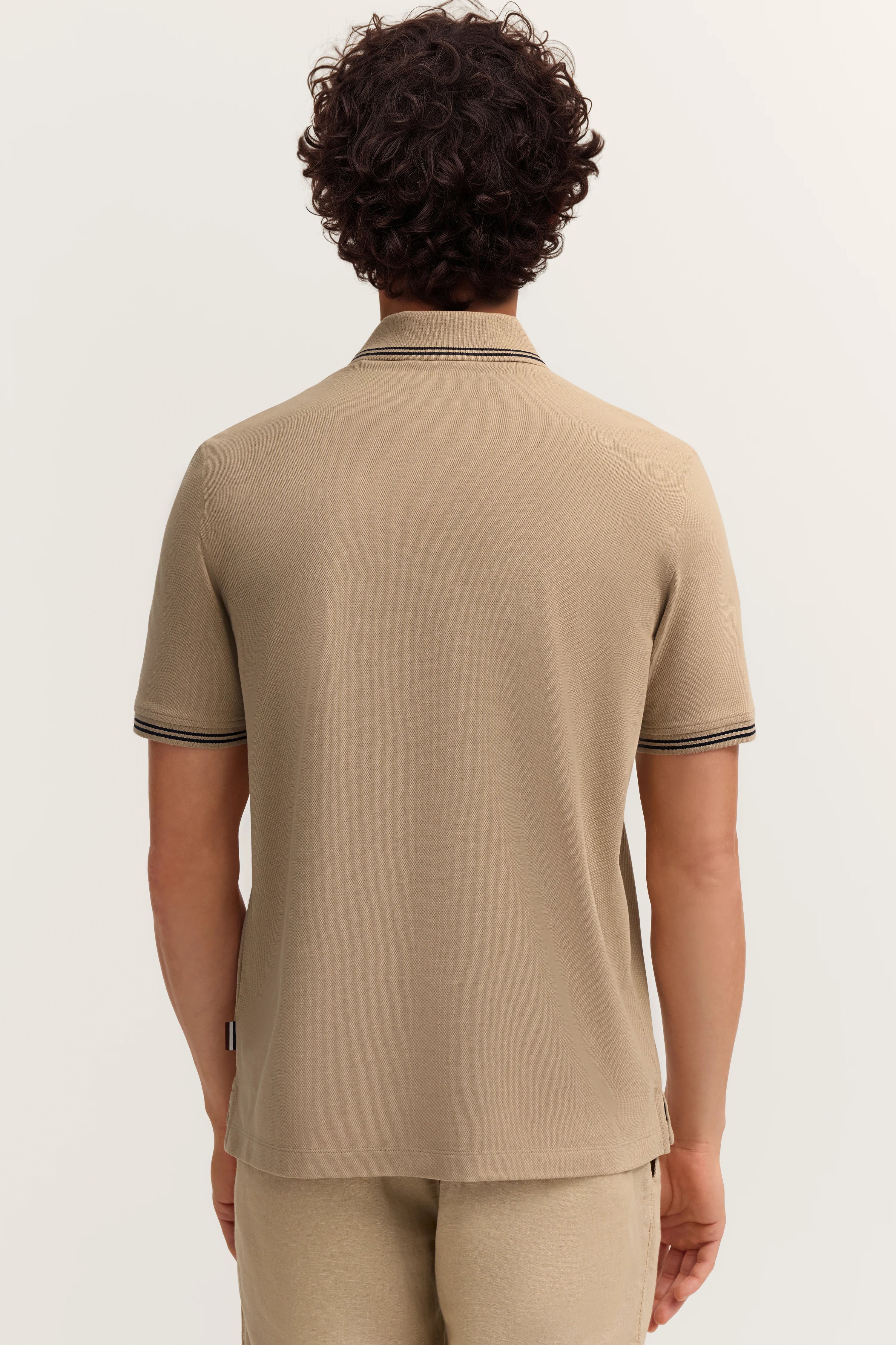 Beiger bugatti Polo, Rückansicht, legeres Modelbild mit entspannter Haltung.