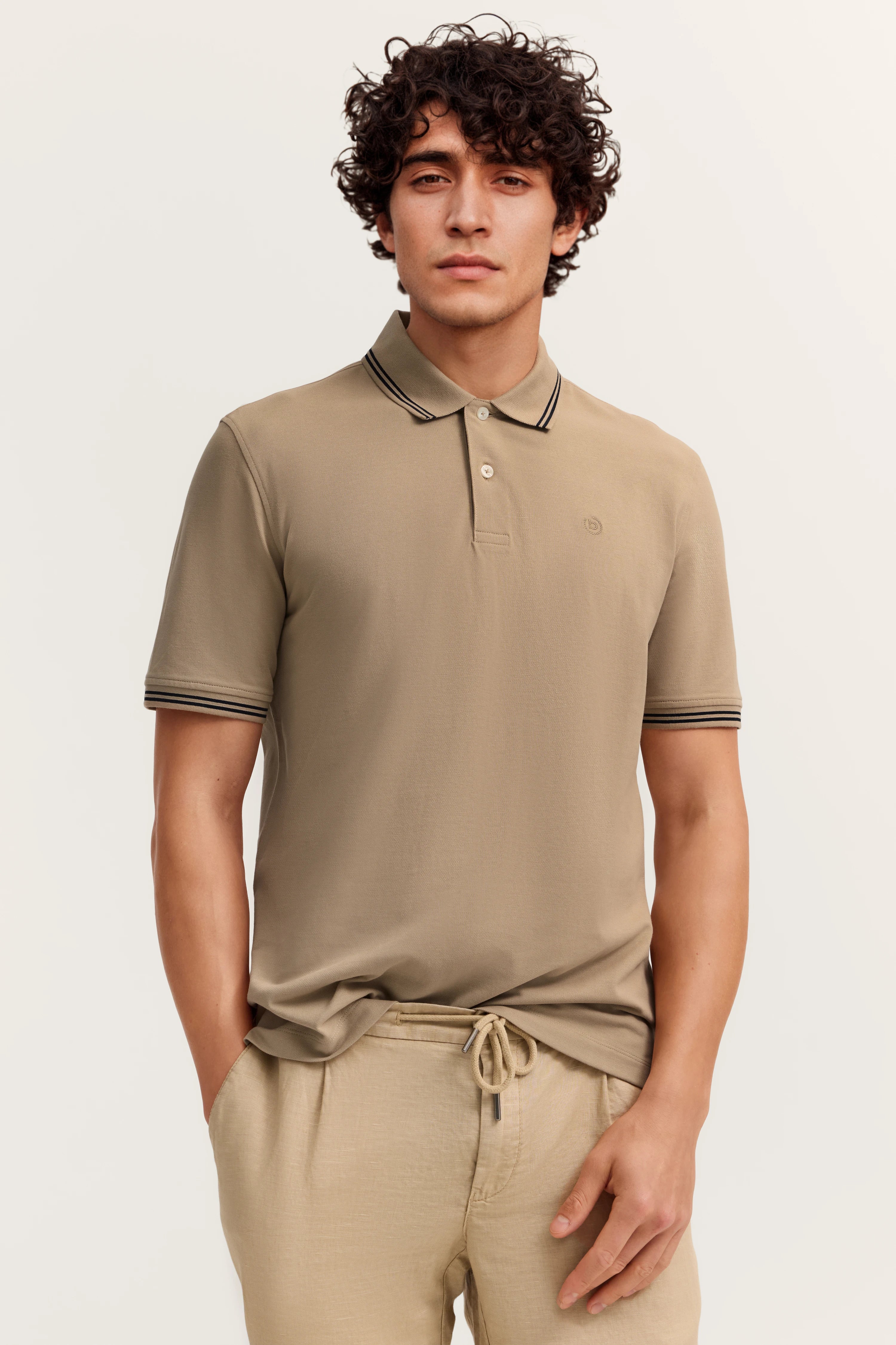 Beiges bugatti Poloshirt und Hose, legeres Modelbild, entspanntes Posing.