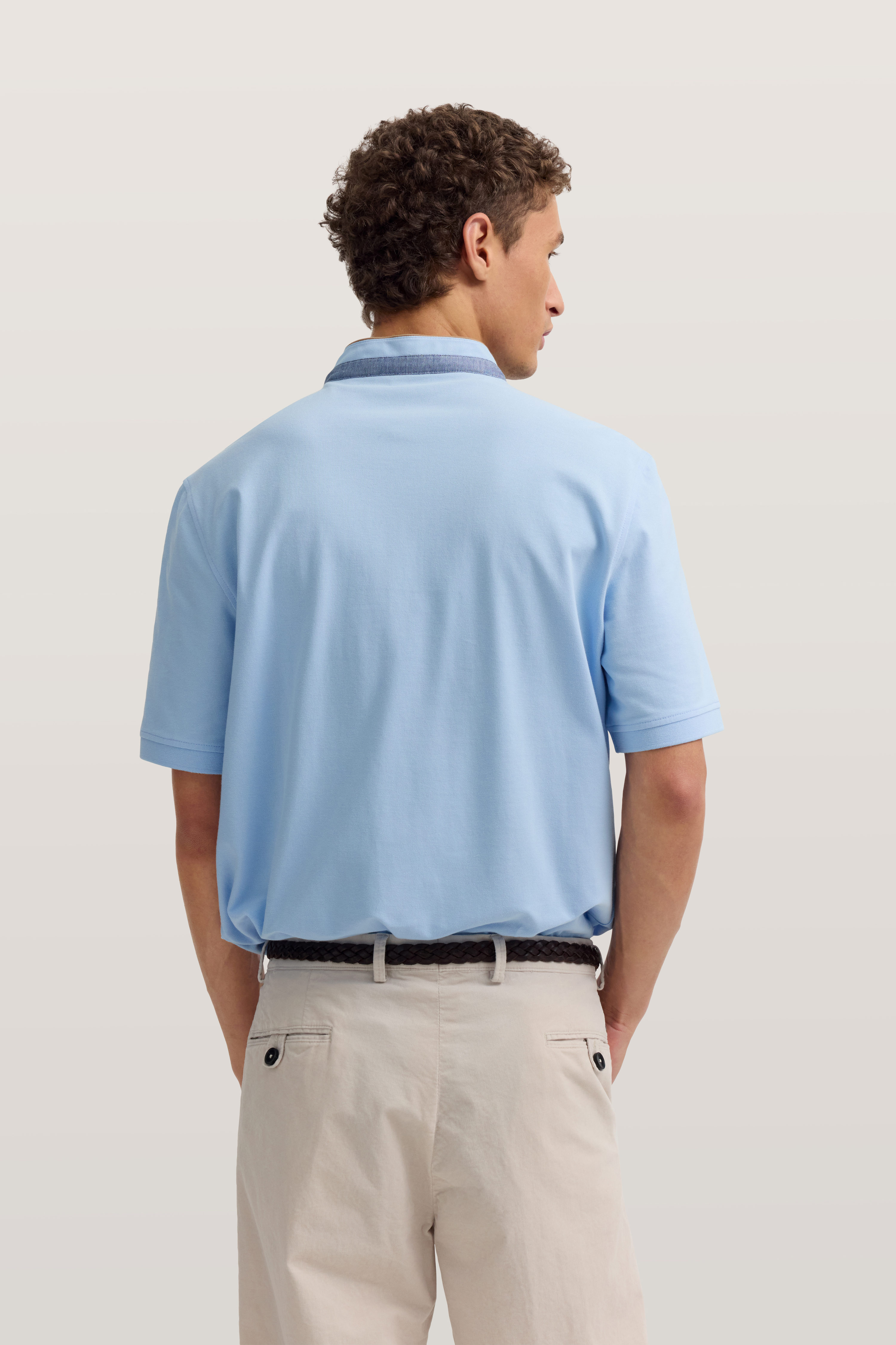 Hellblaues Polo-Shirt und beige Chinos von bugatti, Model von hinten, entspannte Haltung.