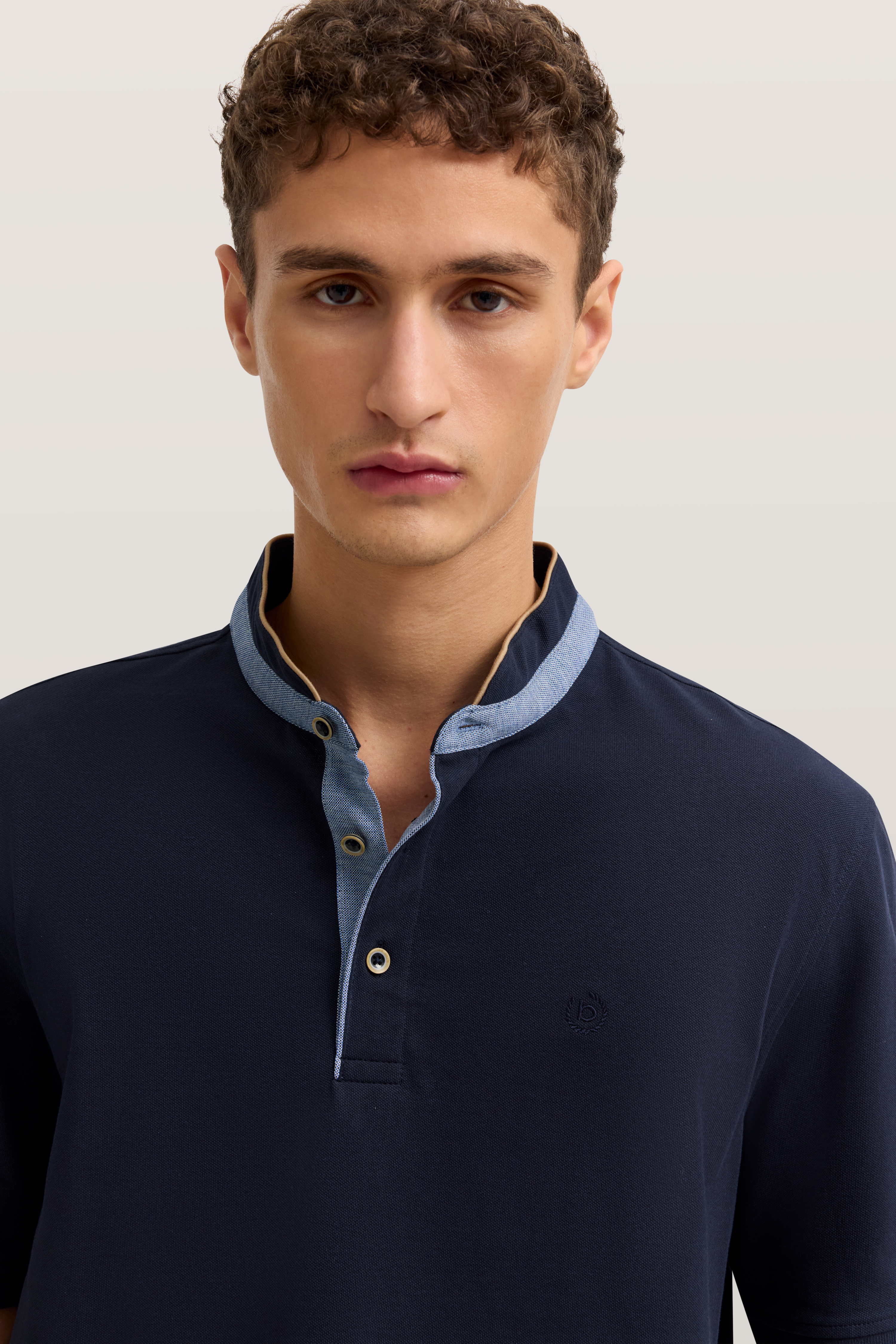 bugatti Modelbild, Mann trägt dunkelblaues Polo mit blauem Kragen, entspanntes Posing.