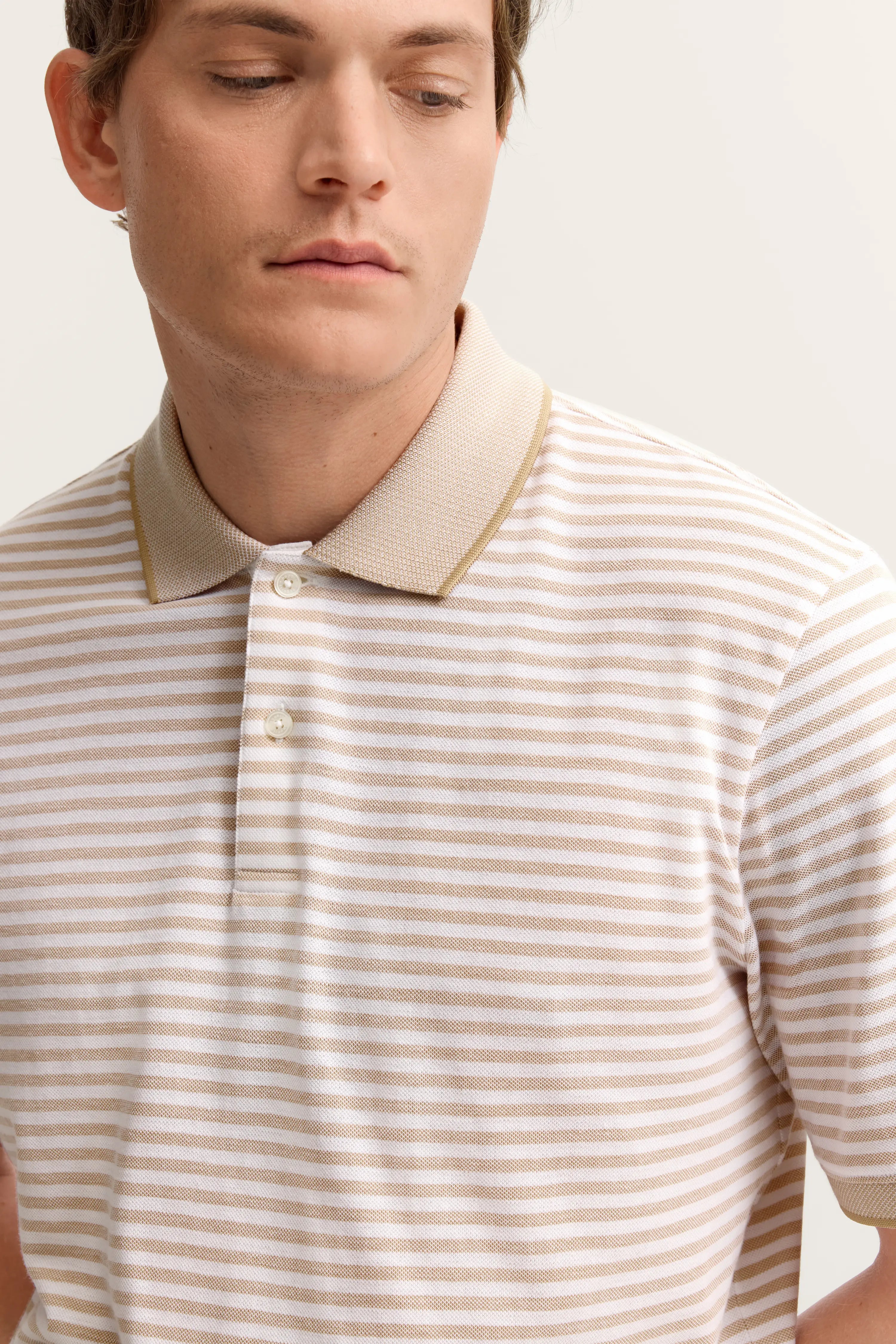 Streifen-Poloshirt in Beige und Weiß, Model frontal, entspannter Blick, bugatti Stil.