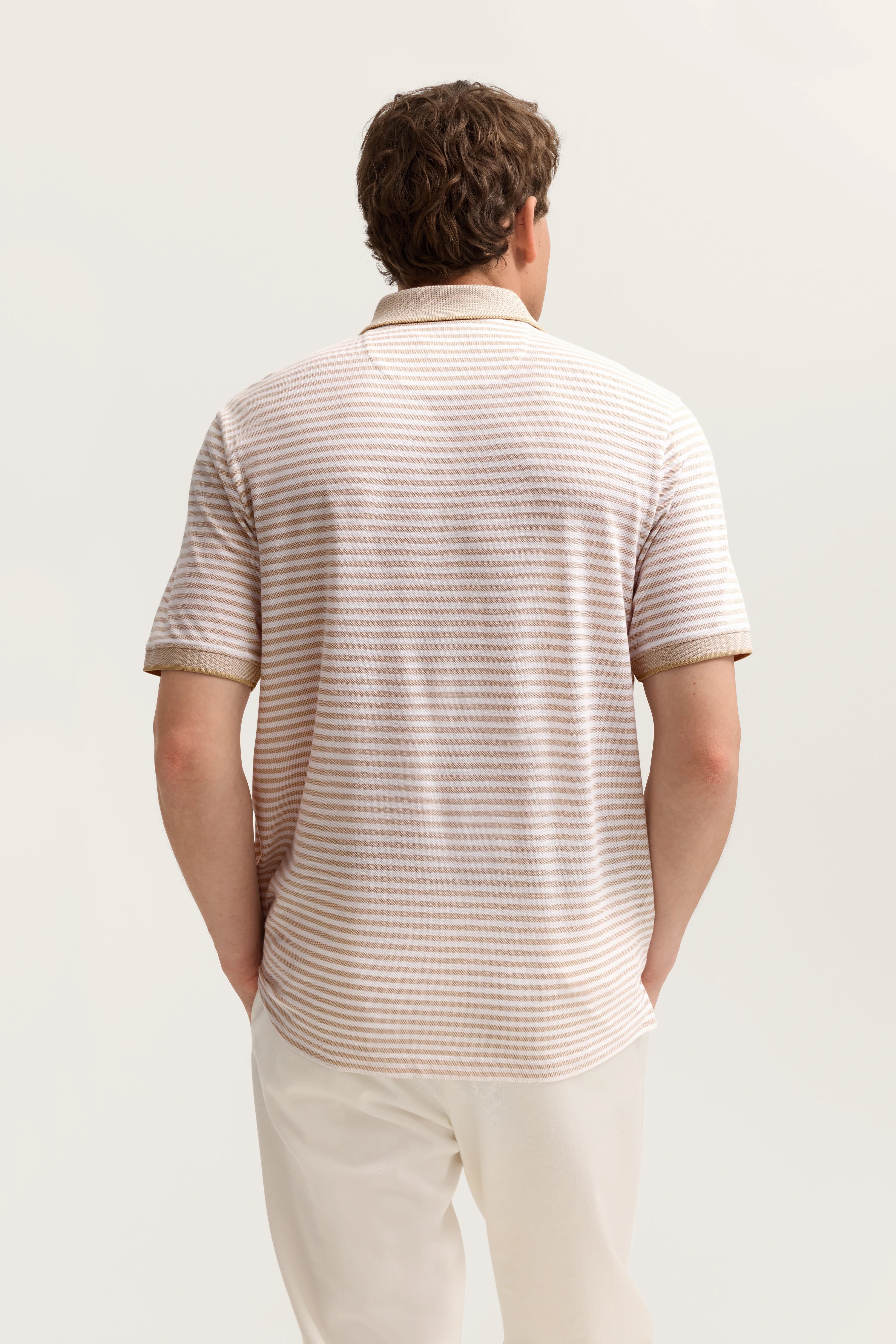 Rückansicht Modelbild mit beige-weiß gestreiftem Polo von bugatti, kombiniert mit weißen Hosen.
