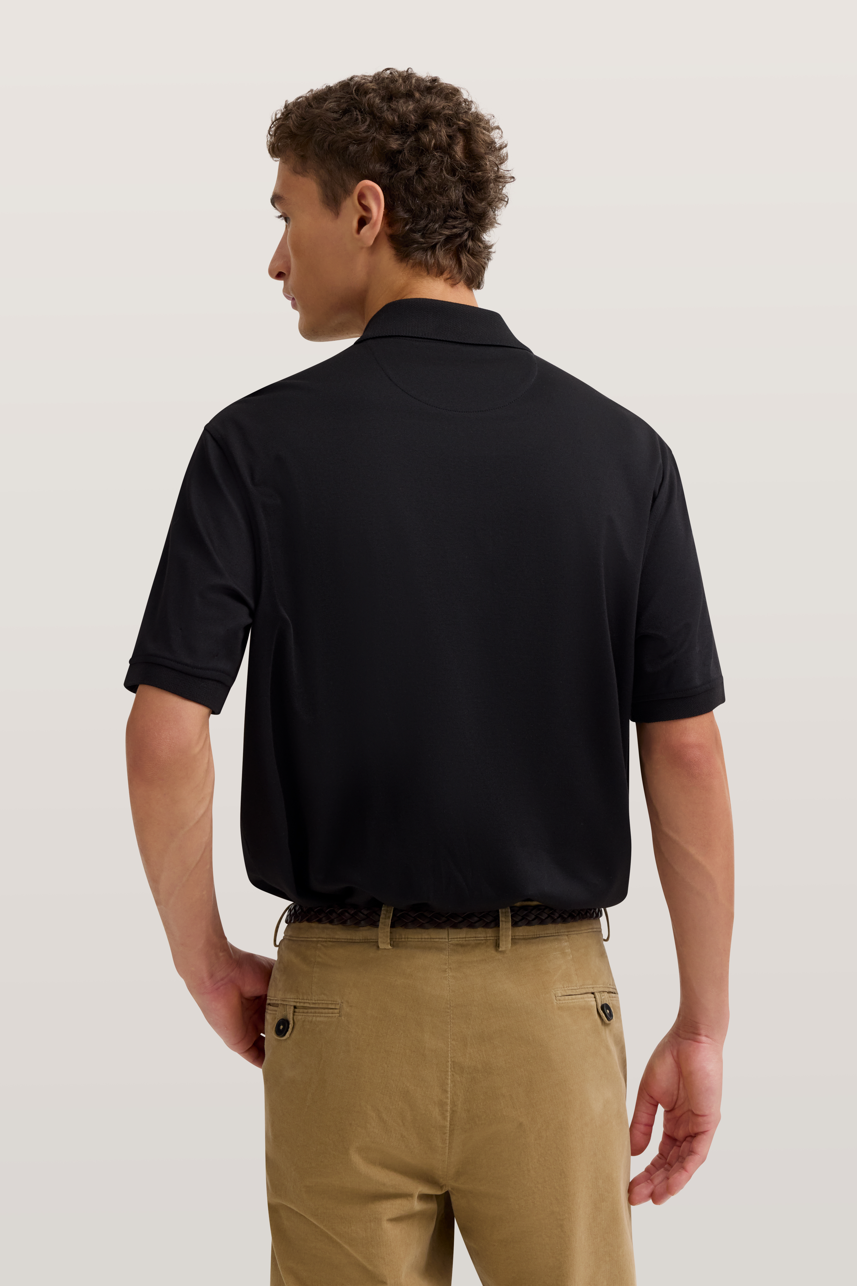 Schwarzes Polohemd, beigefarbene Chinos, Model von hinten, entspannte Pose, bugatti Stil.