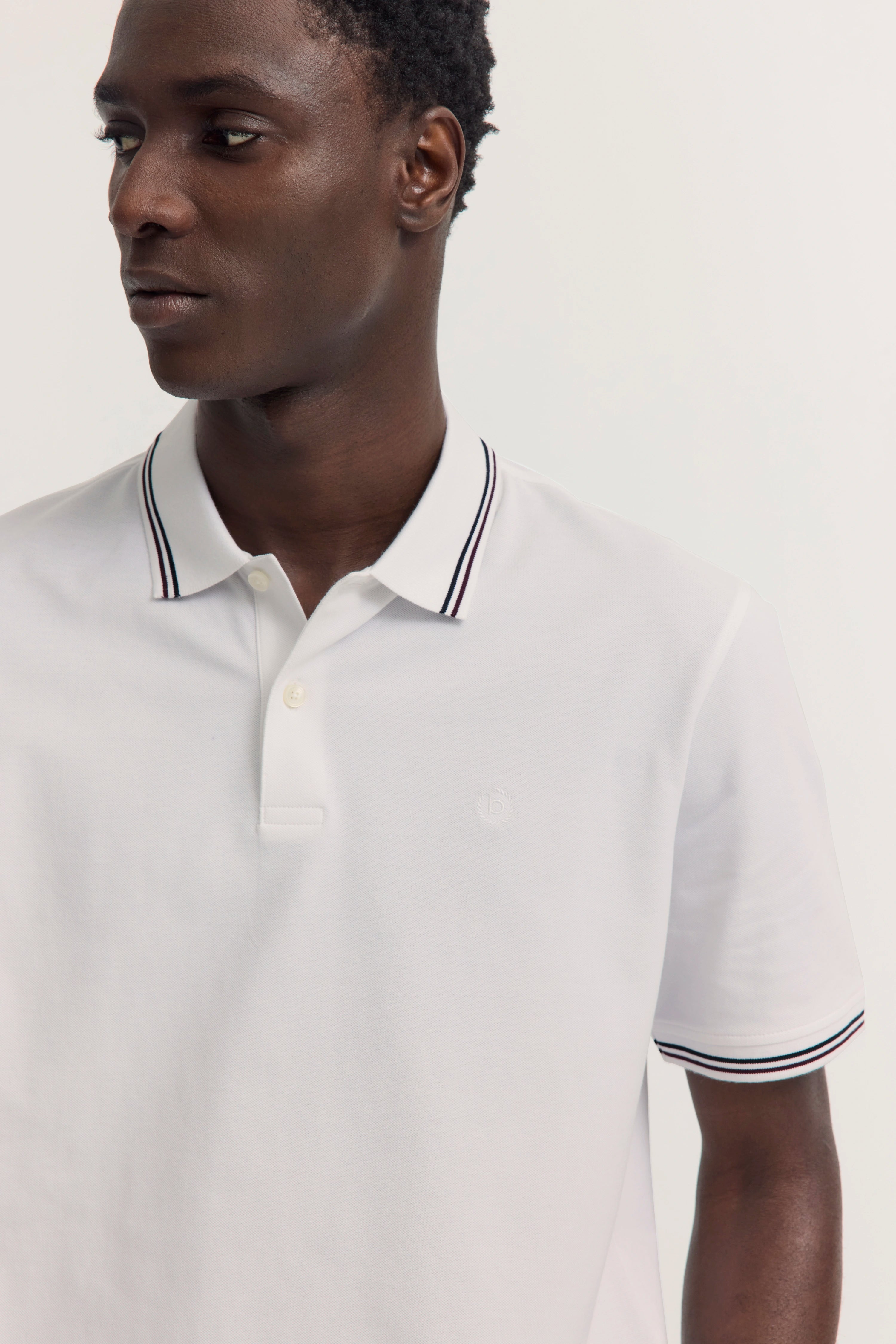 Weißes Polohemd und beige Hose, Rückansicht Model, lässig und stilvoll von bugatti.