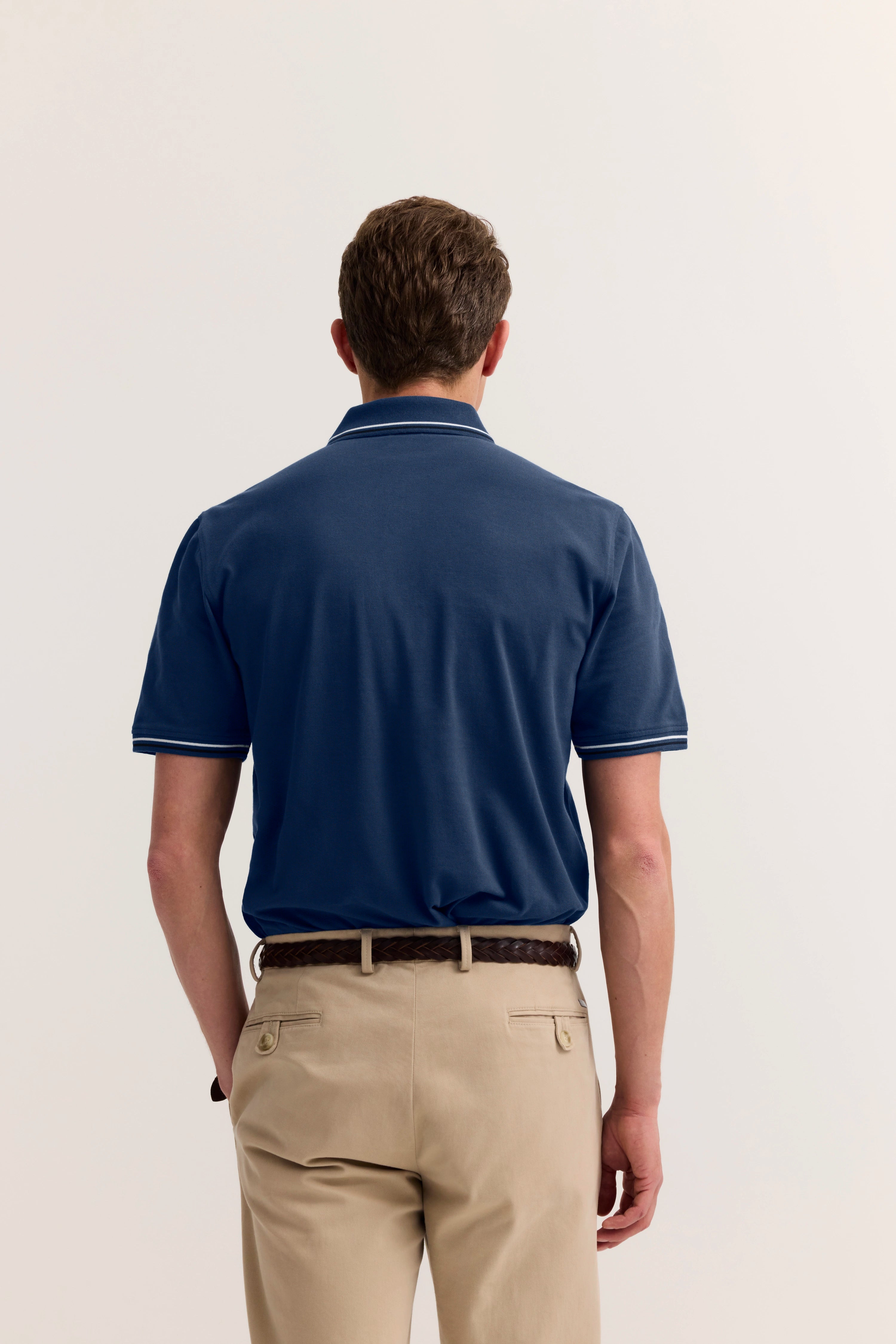 Blaues Polo und beige Hose von bugatti, Rückansicht, legeres Modelbild.