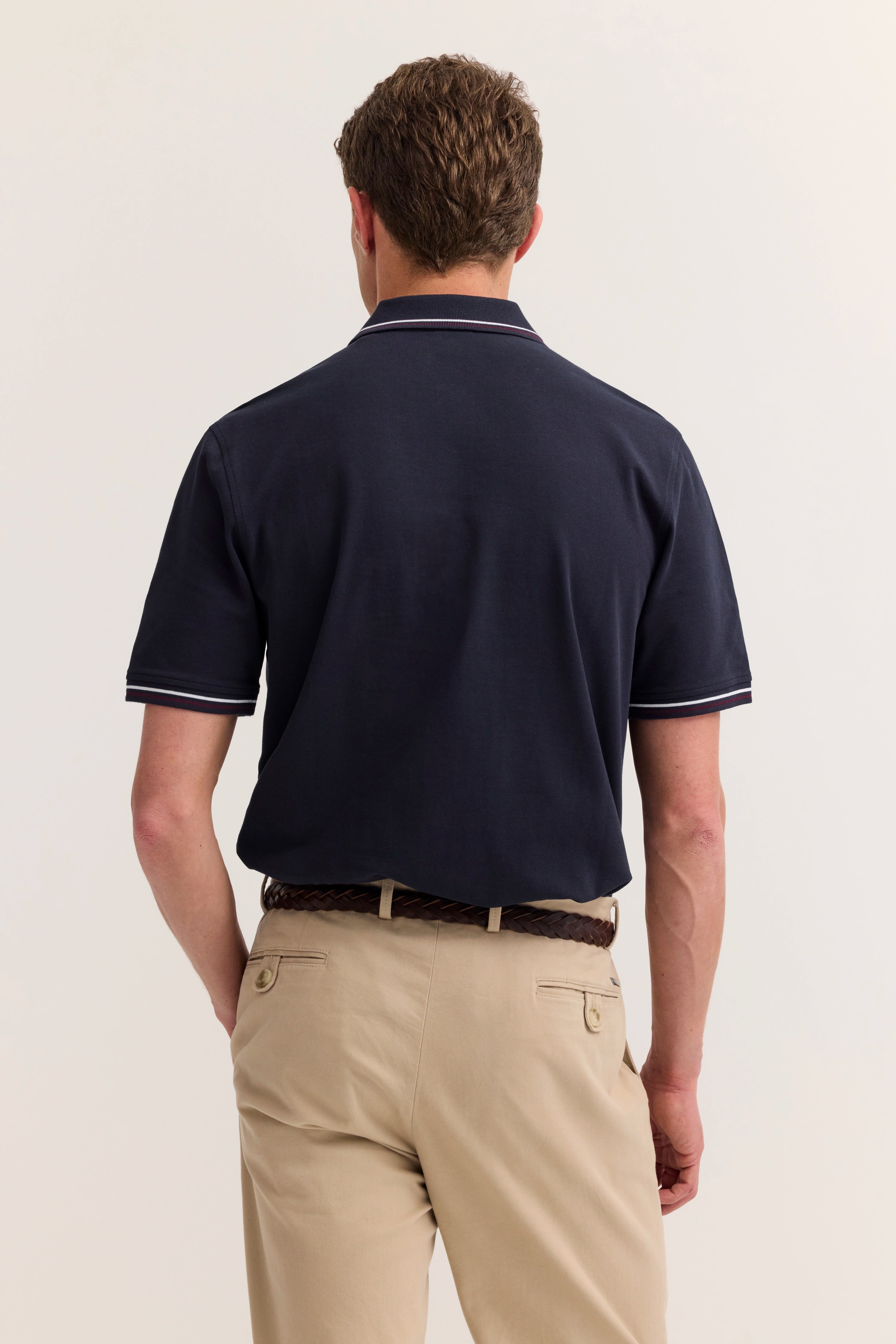Navy Polo und beige Chinos von bugatti, Model von hinten, lässige Pose, eleganter Freizeitlook.