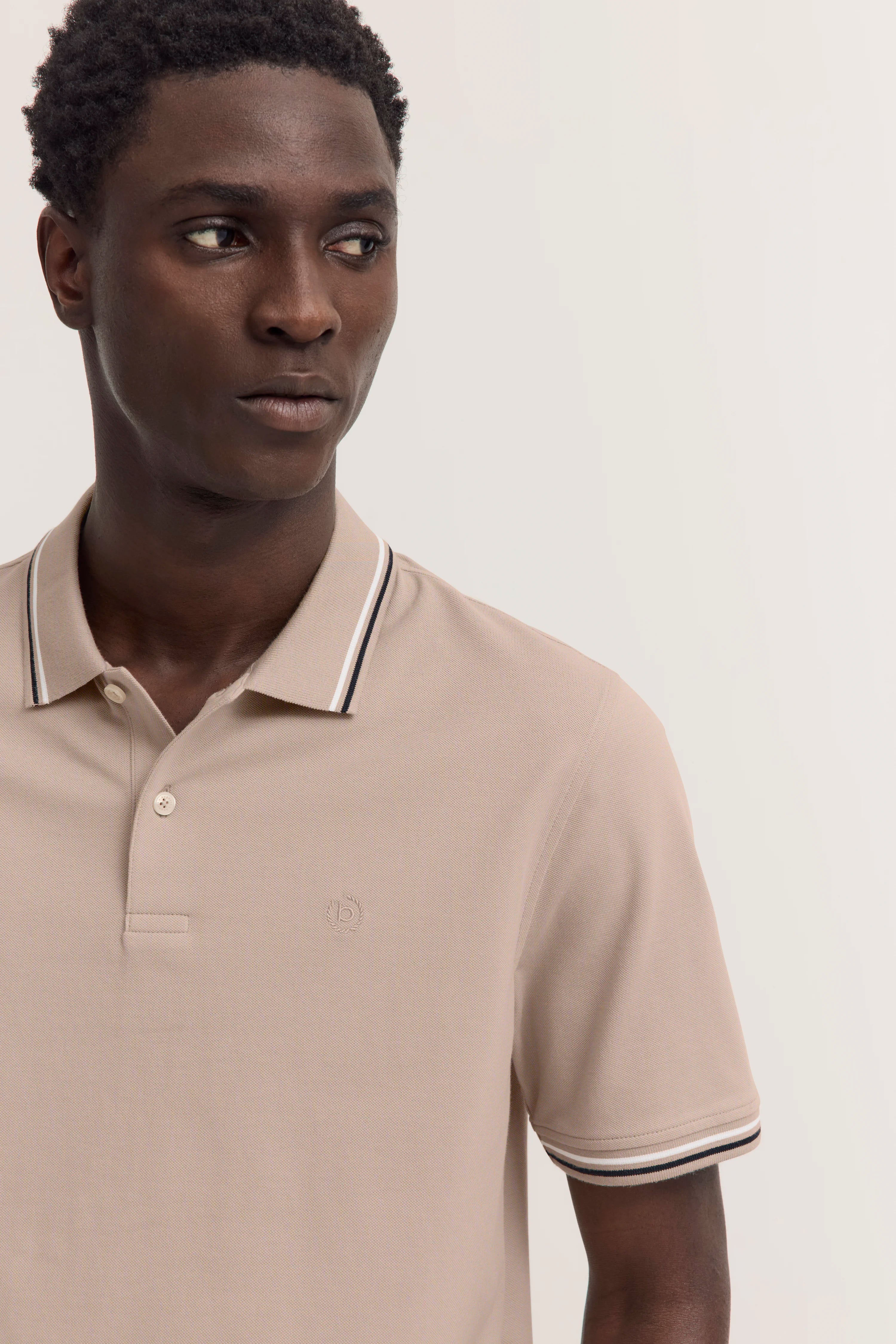 Beiges bugatti Polohemd, Modelbild, Blick zur Seite, klassisches Design, eleganter Stil.