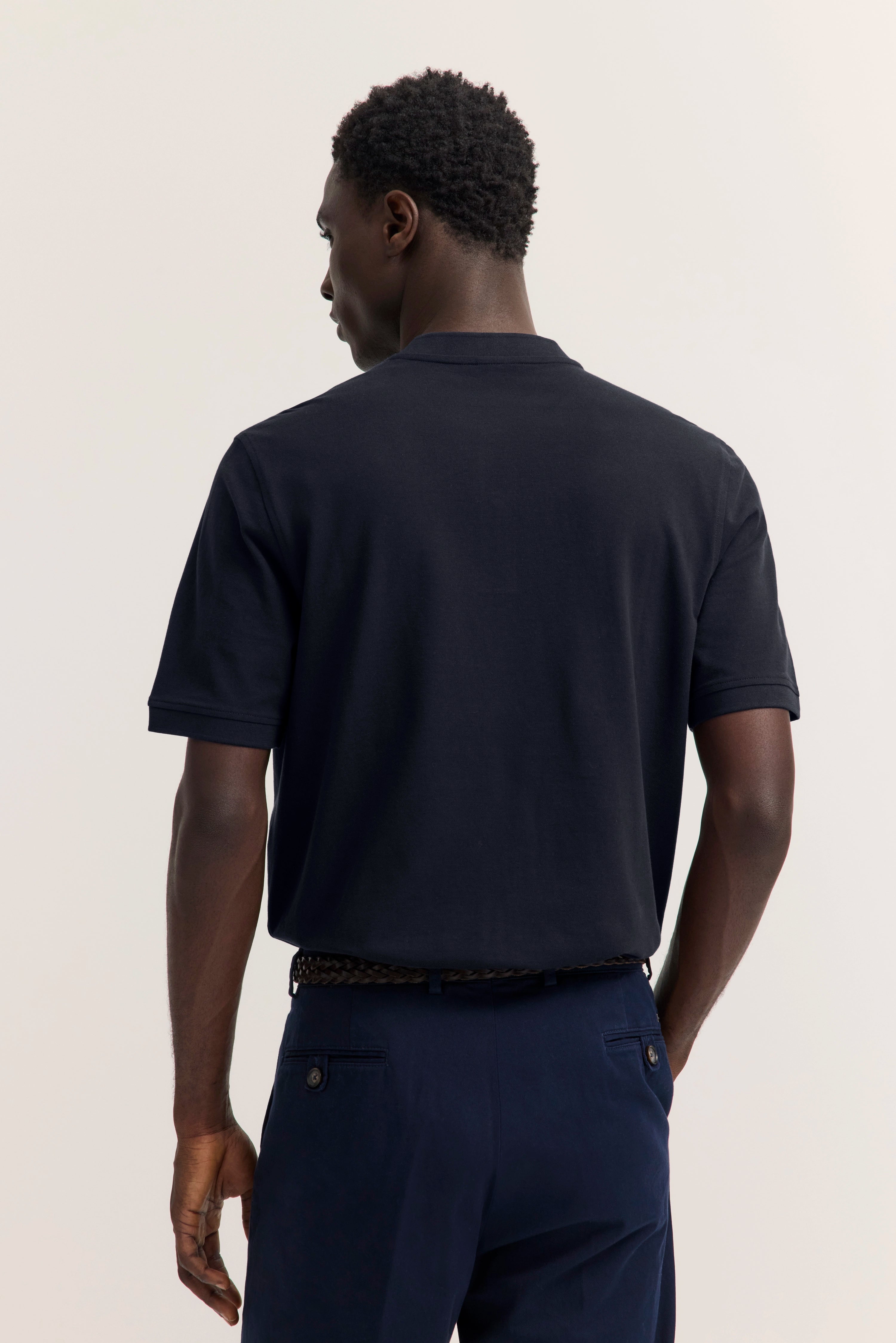 Schwarzes bugatti T-Shirt und blaue Hose, Modell von hinten, entspanntes Posing.
