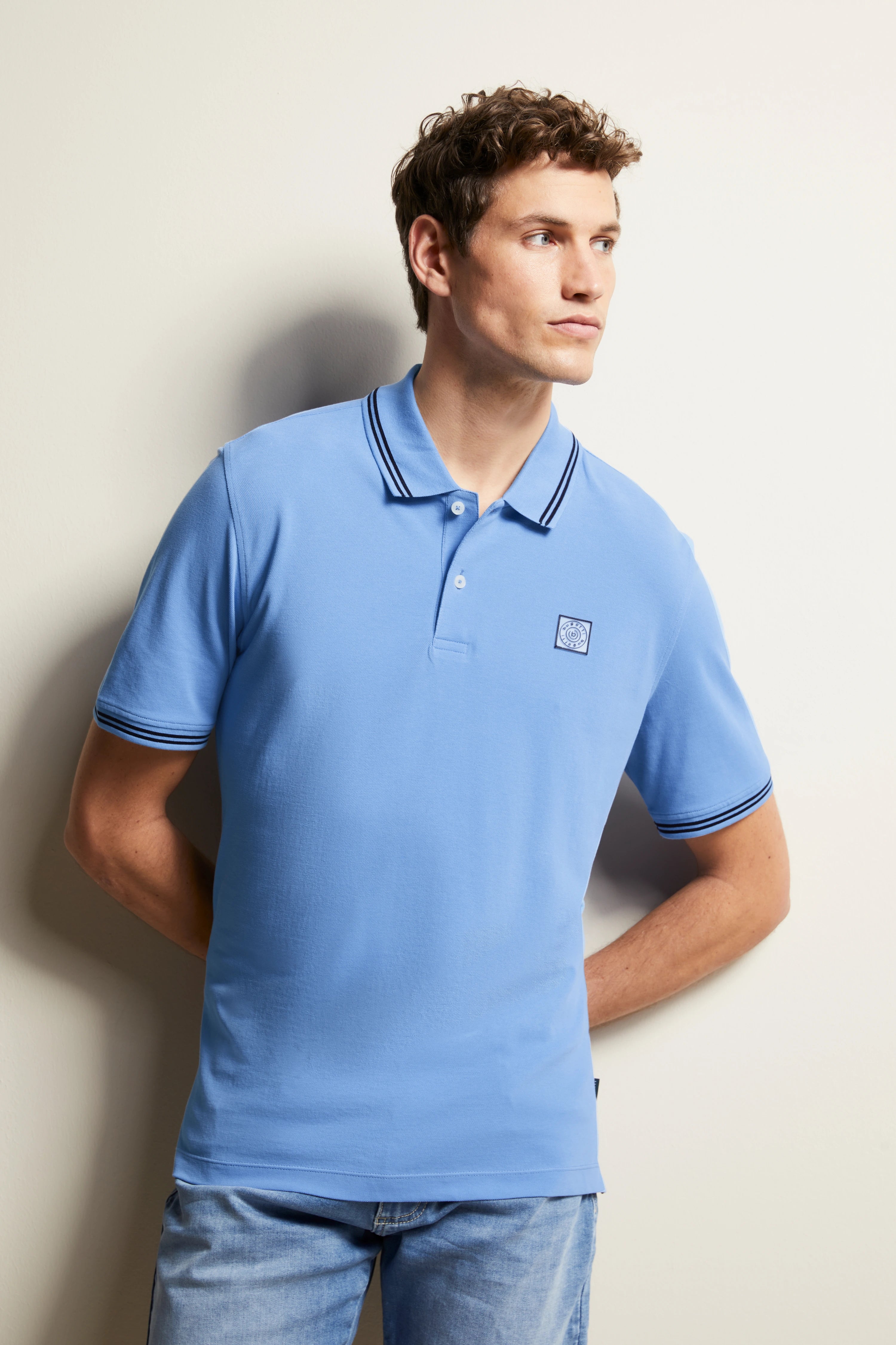 bugatti blue polo, model posing casually, hands behind back, stylish elegance.