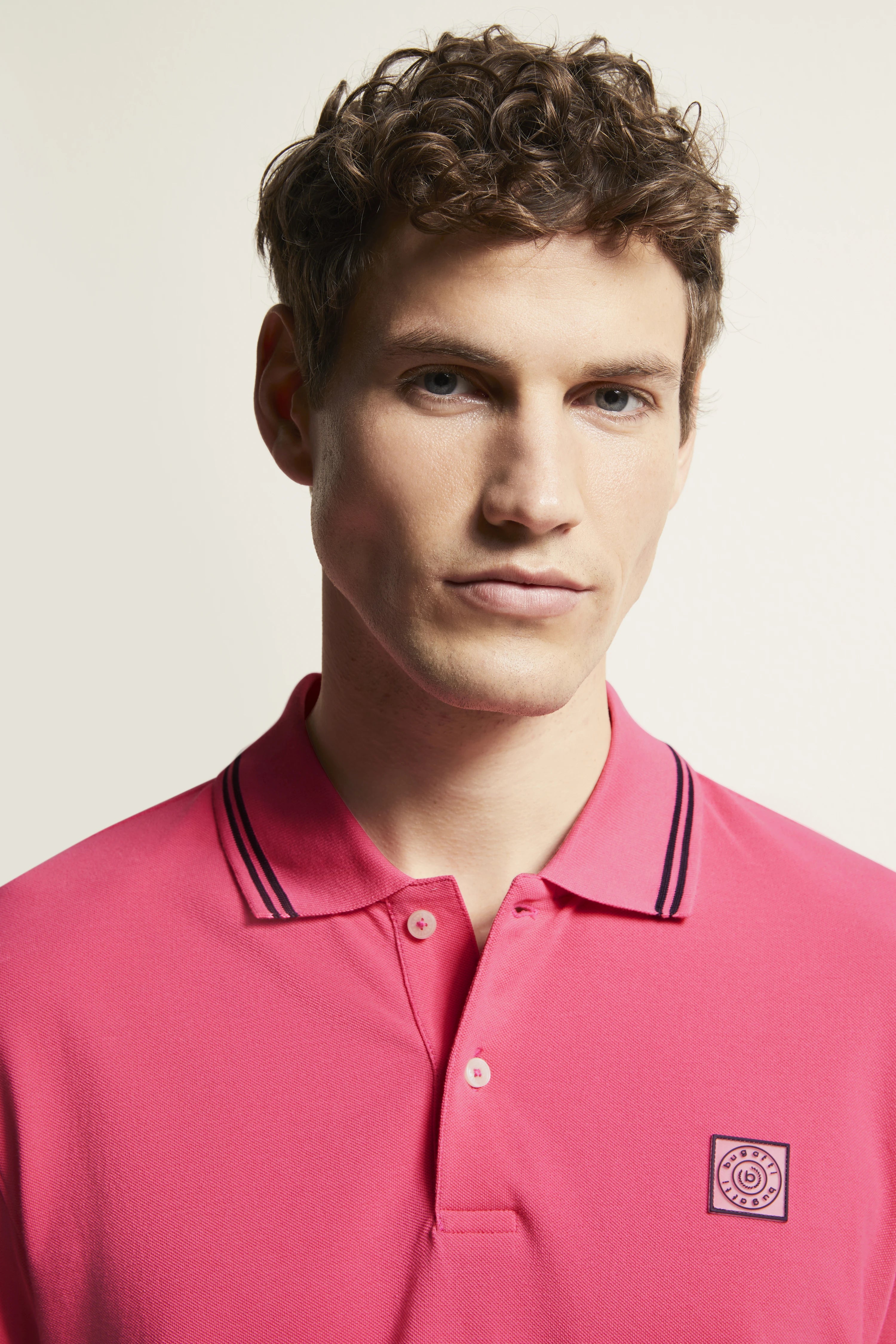 bugatti pink polo shirt with black collar, model in relaxed pose.