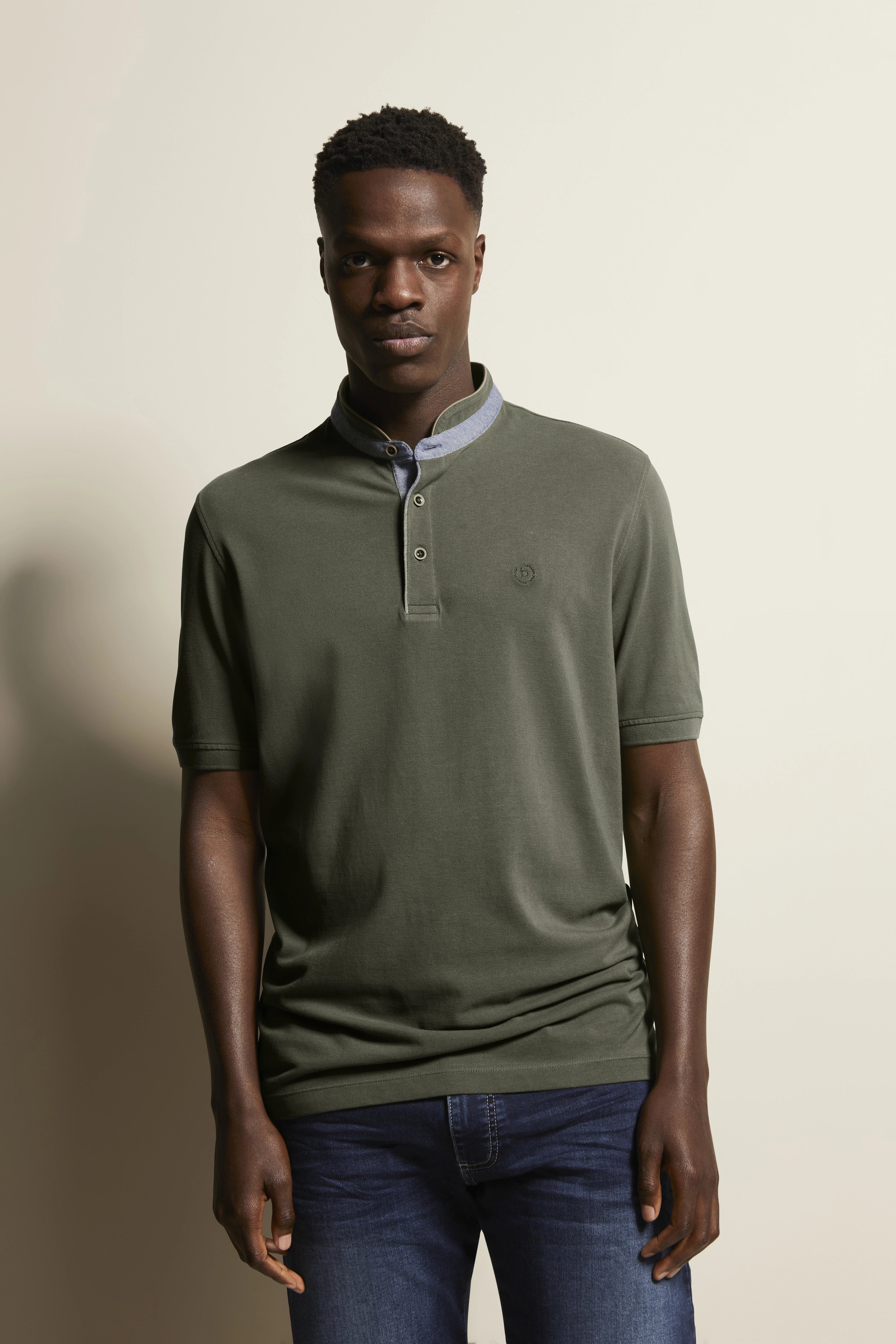 Alttext: Model trägt olivgrünes bugatti Poloshirt und blaue Jeans, legeres Posing.