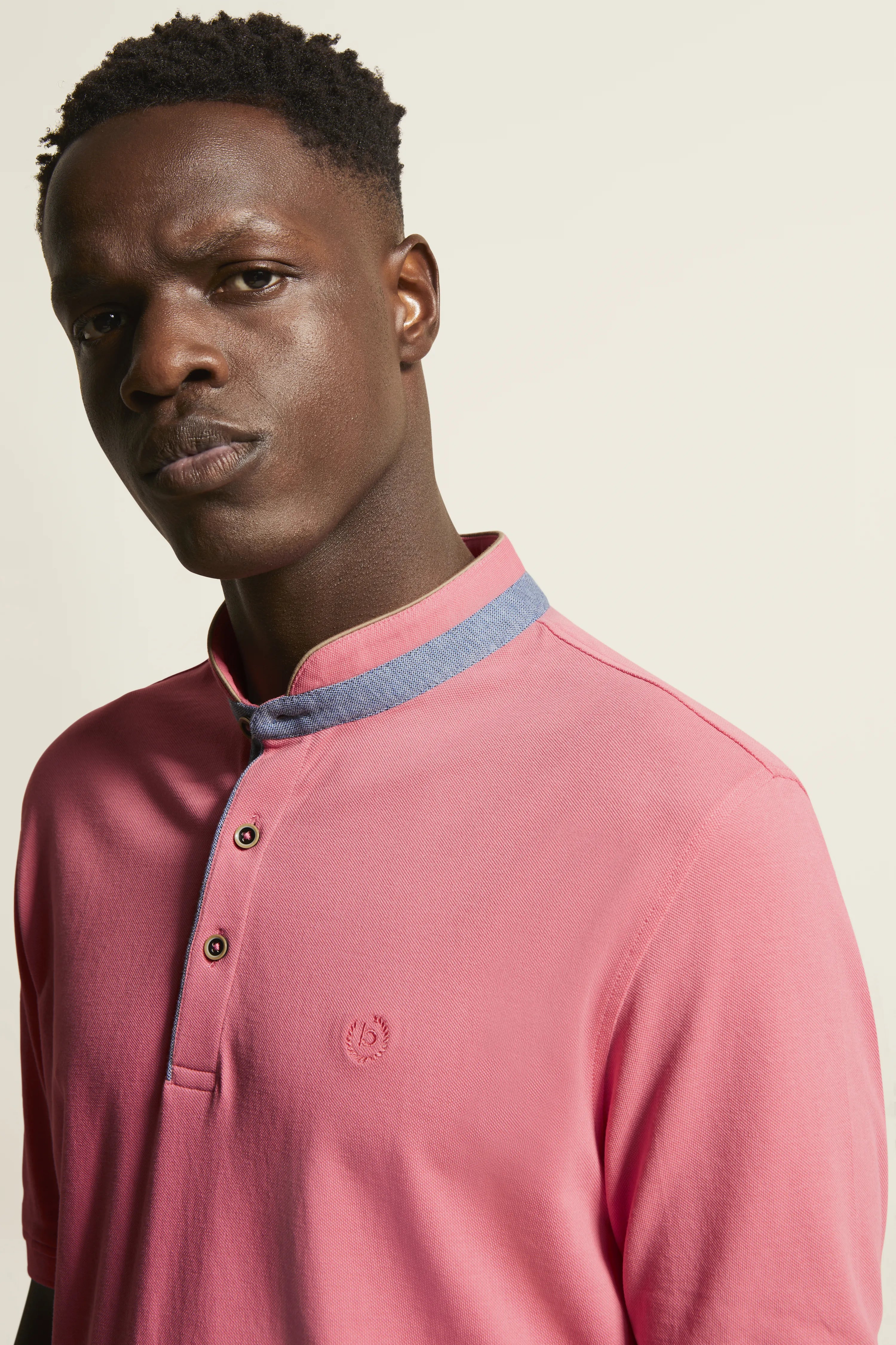 "bugatti Poloshirt in Rosa mit blauem Kragen, Modelbild im legeren Look, entspannte Pose."