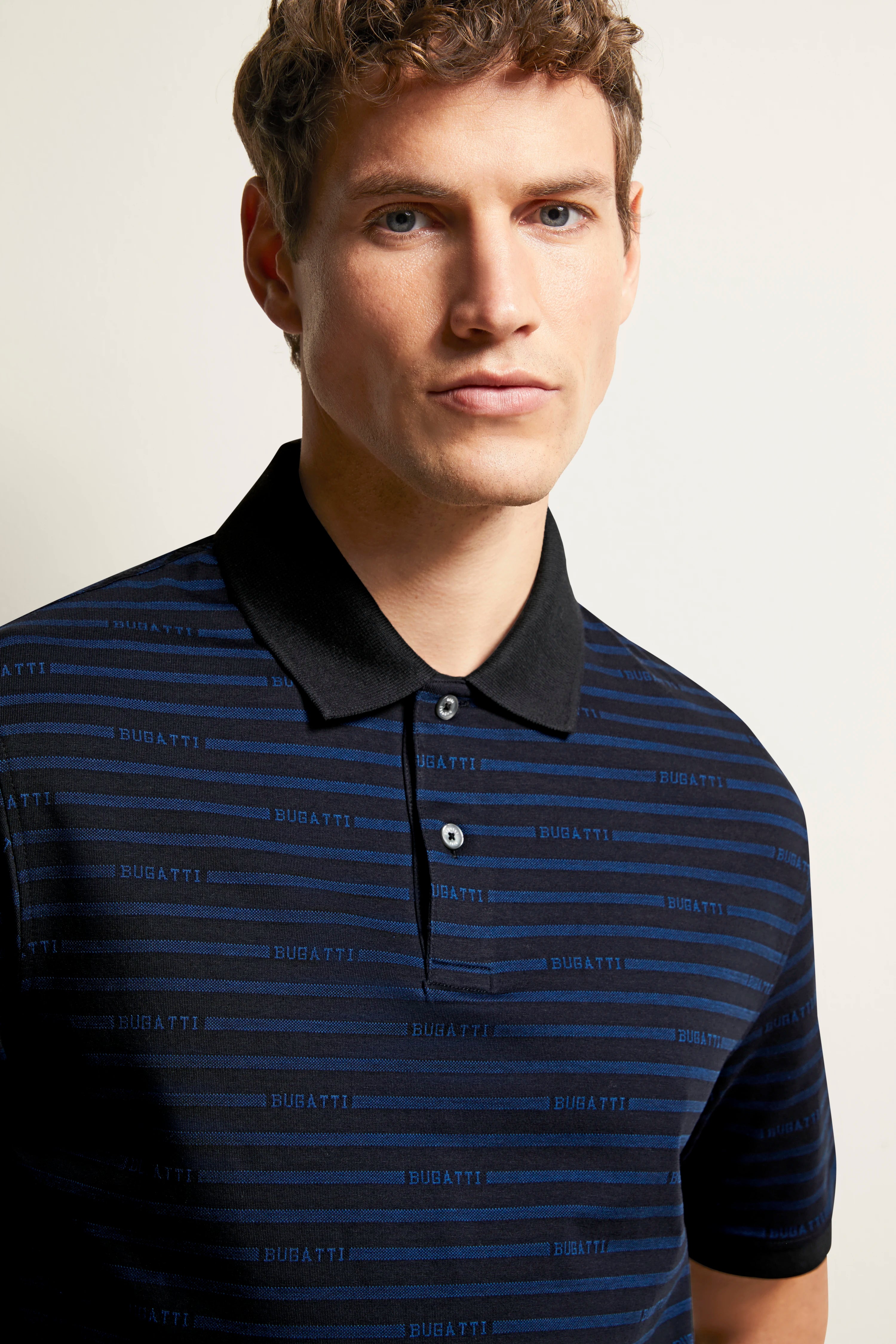 bugatti dark blue striped polo shirt, model in relaxed pose.