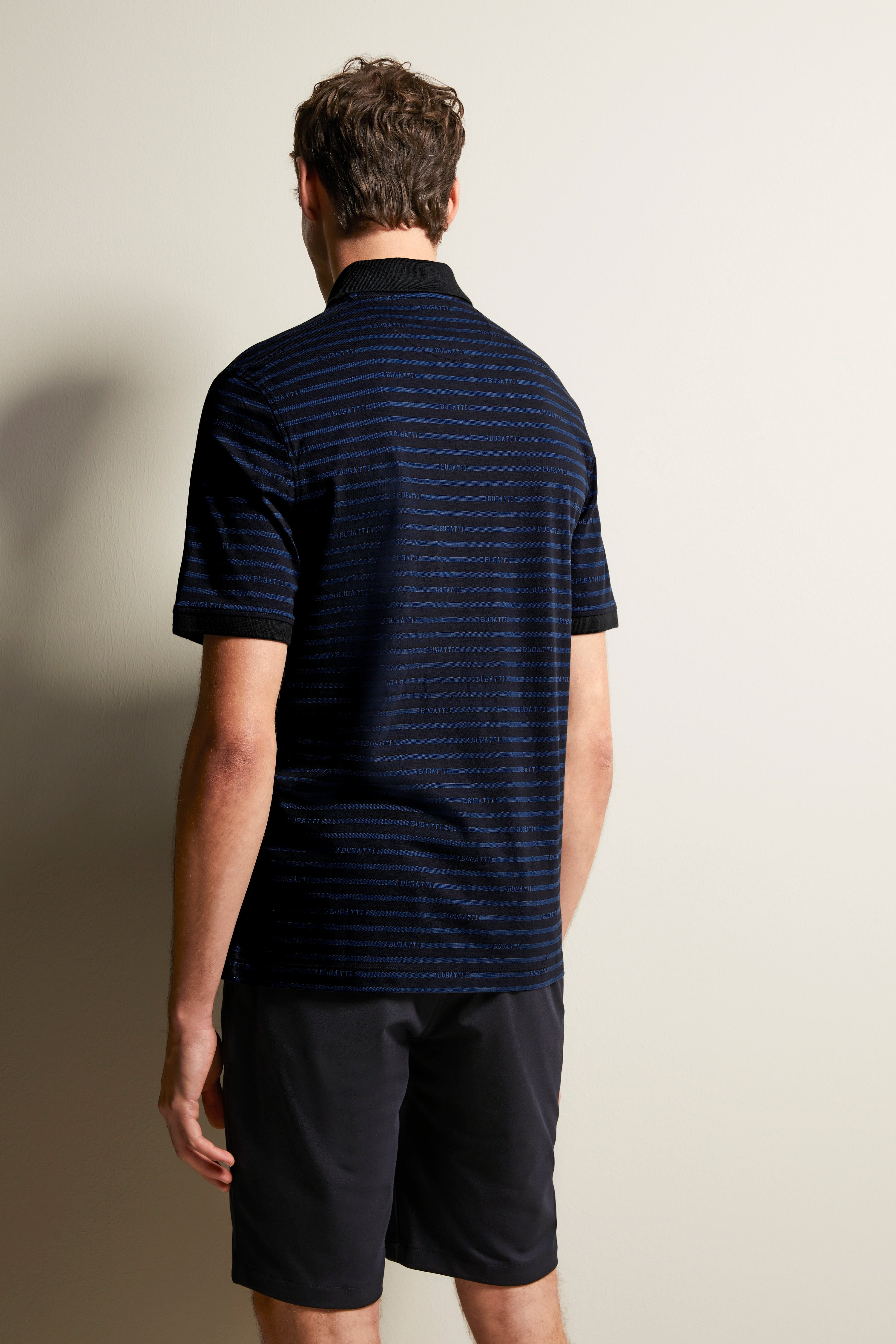 Navy-blue striped polo, black collar, black shorts, rear view, relaxed model.