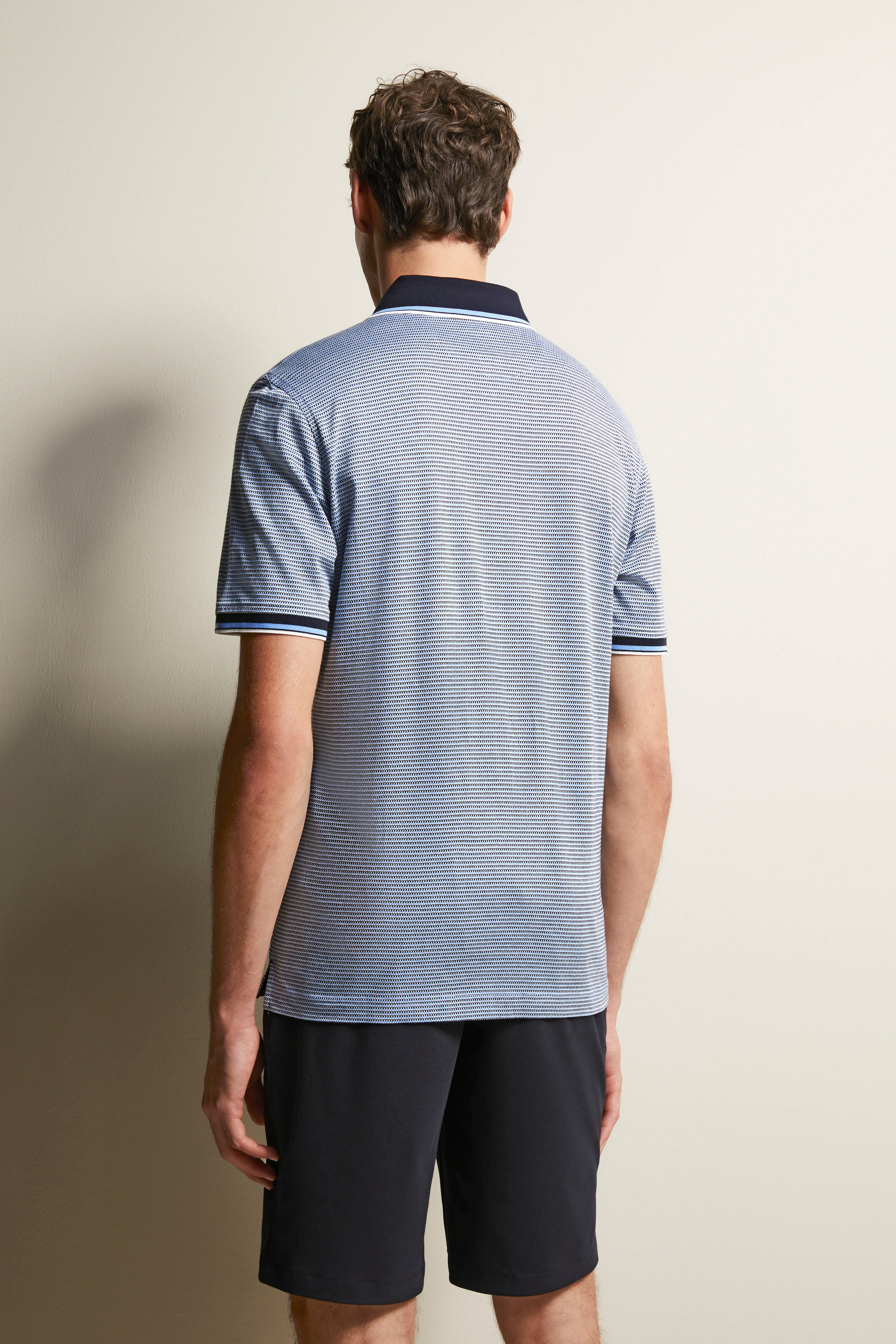 bugatti polo-shirt blauw-wit gestreept, model van achteren, gecombineerd met donkerblauwe shorts.