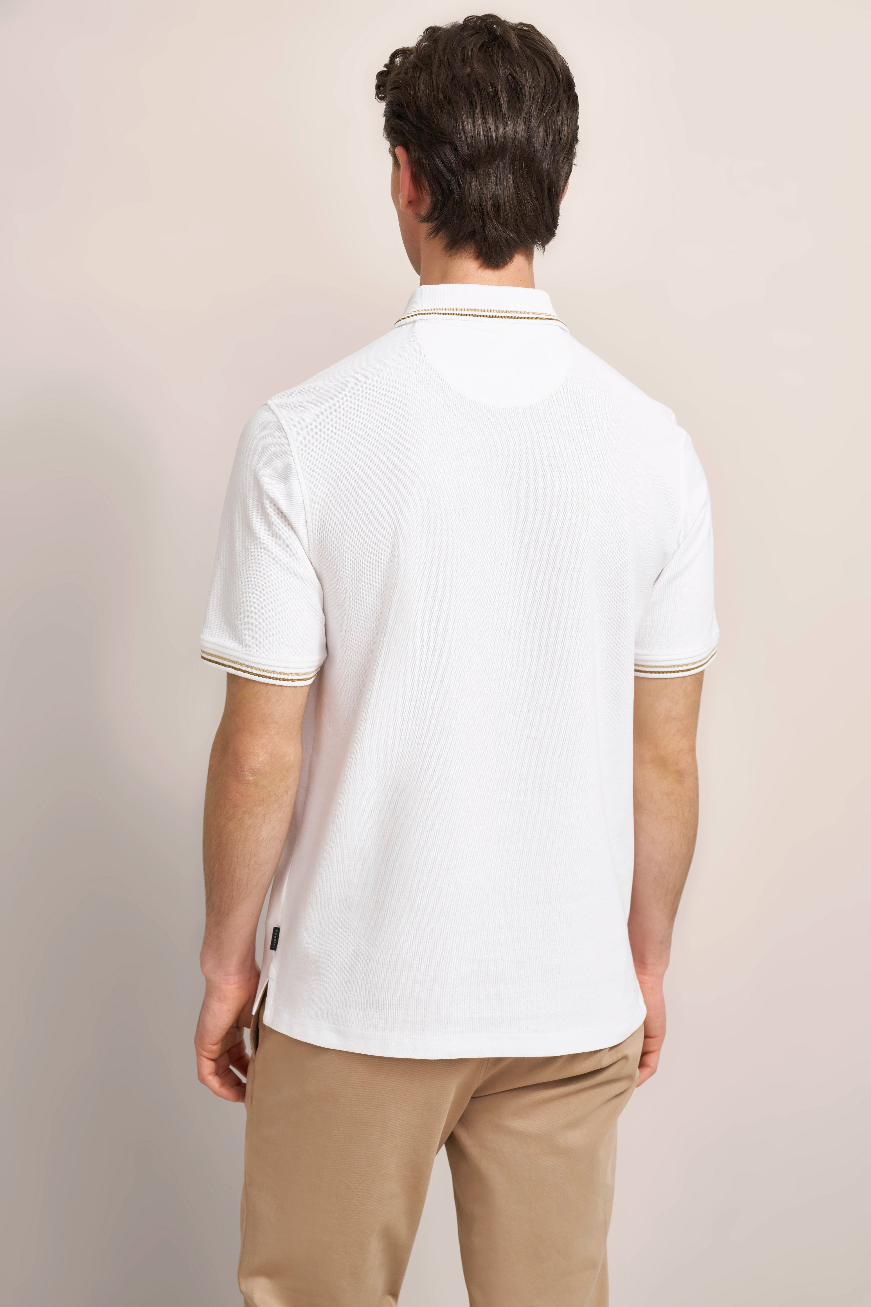 Weißes Polohemd und beige Hose von bugatti, Rückenansicht, legeres Modelbild.