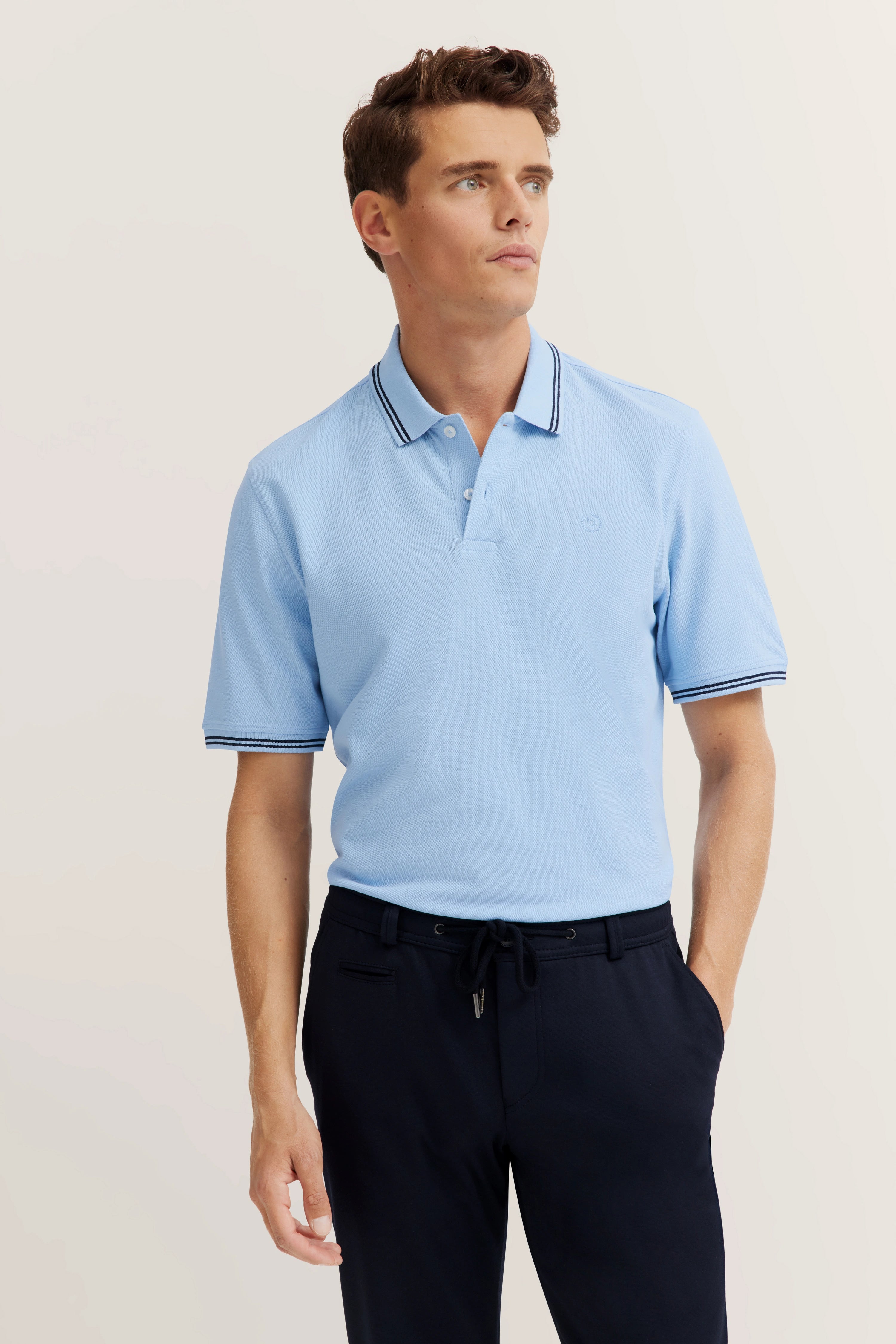 bugatti model in light blue polo shirt, black pants, casual pose, exuding style and timeless sophistication.