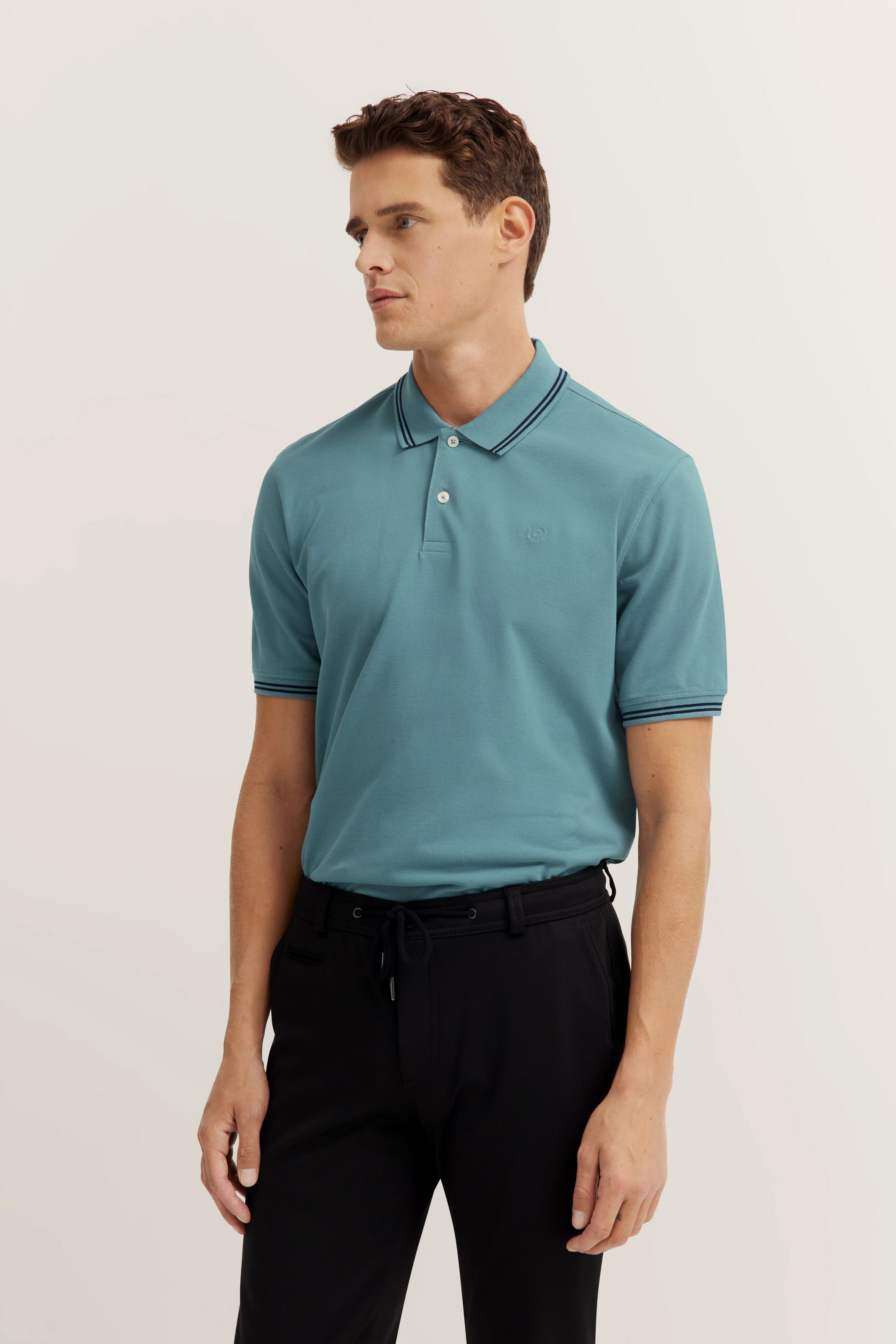 Model in light blue polo shirt and black pants, standing pose, embodying bugatti style.