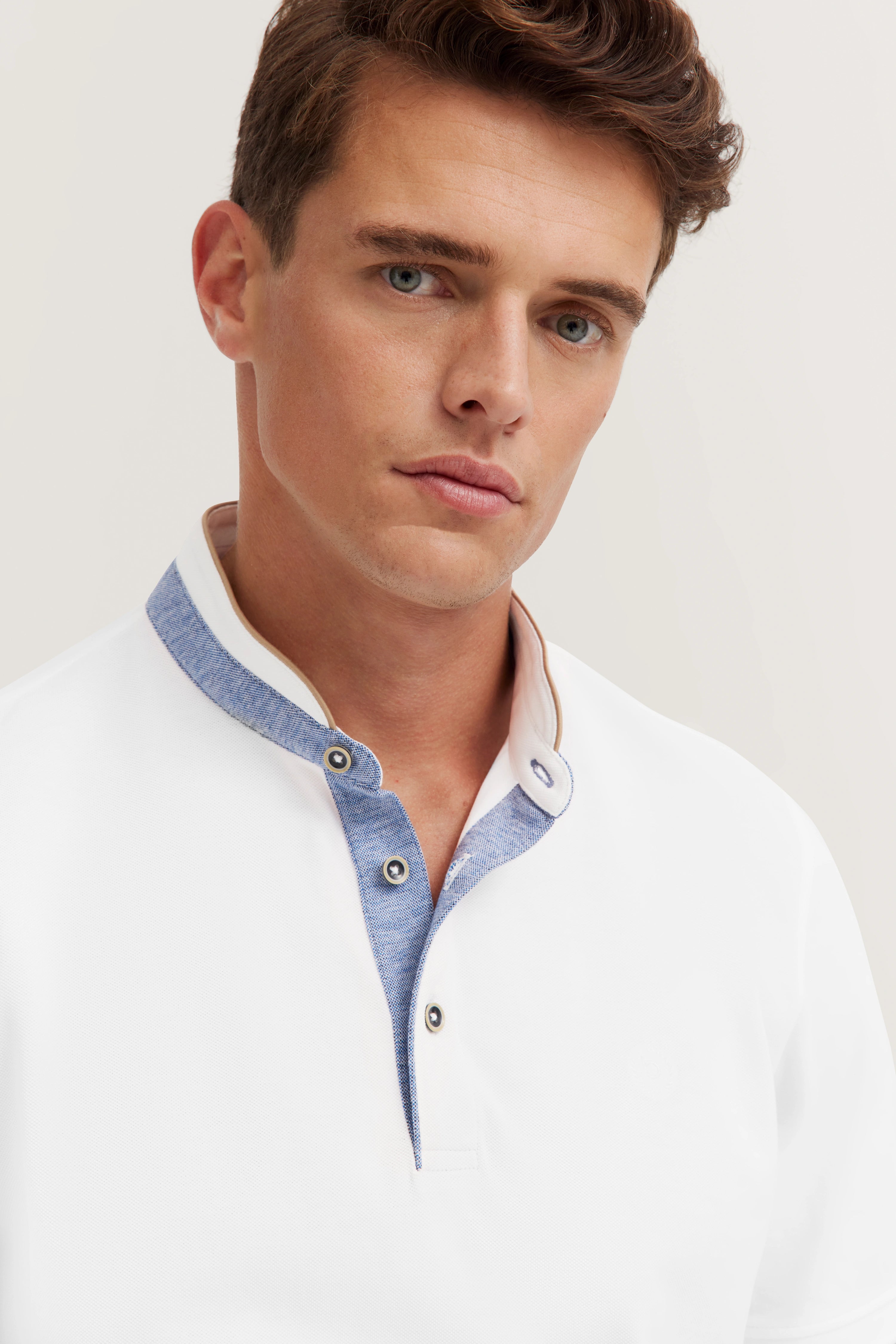 White bugatti polo shirt with blue collar, model with relaxed expression.