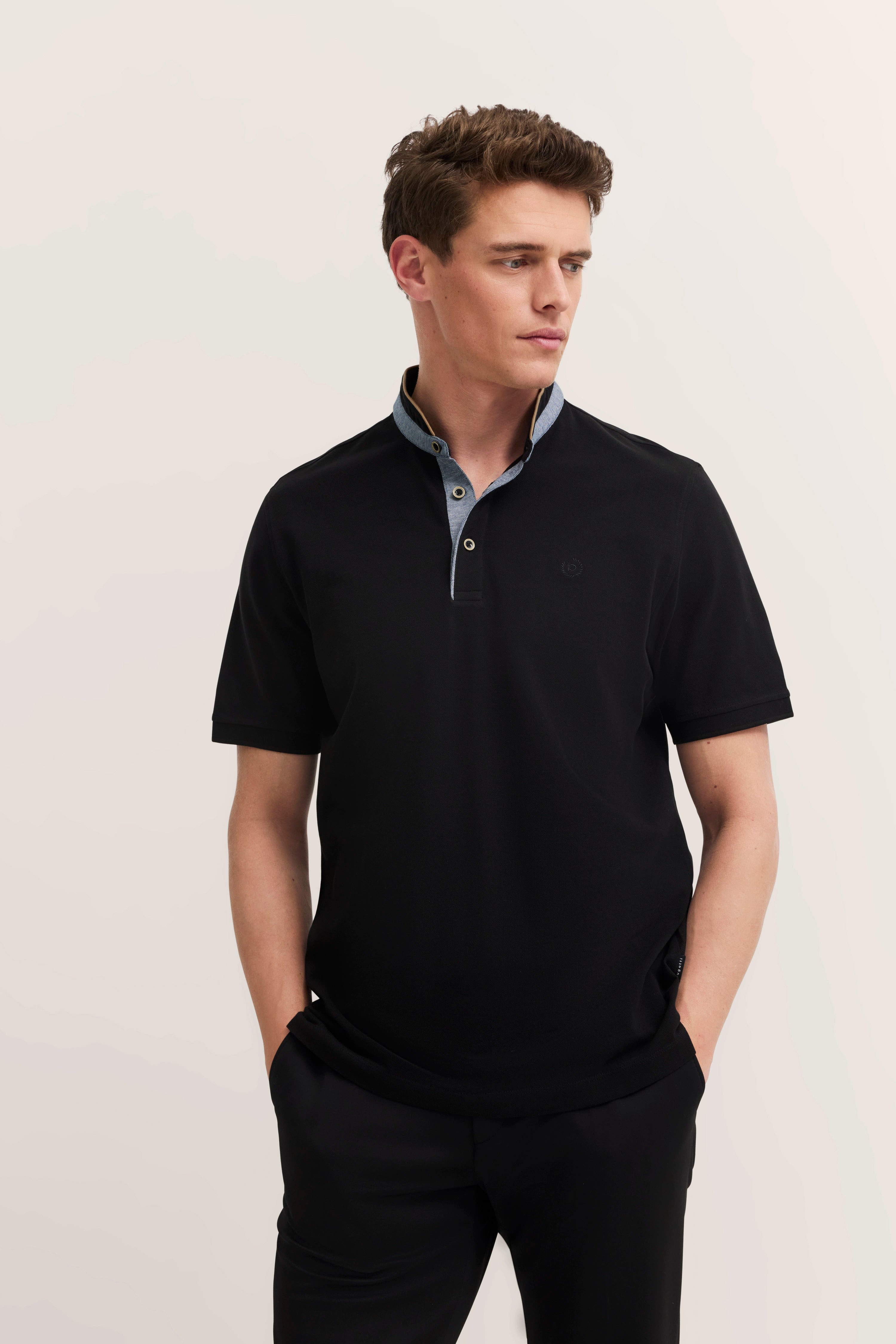 Black bugatti polo shirt, blue collar, model in casual pose, hands in pockets.
