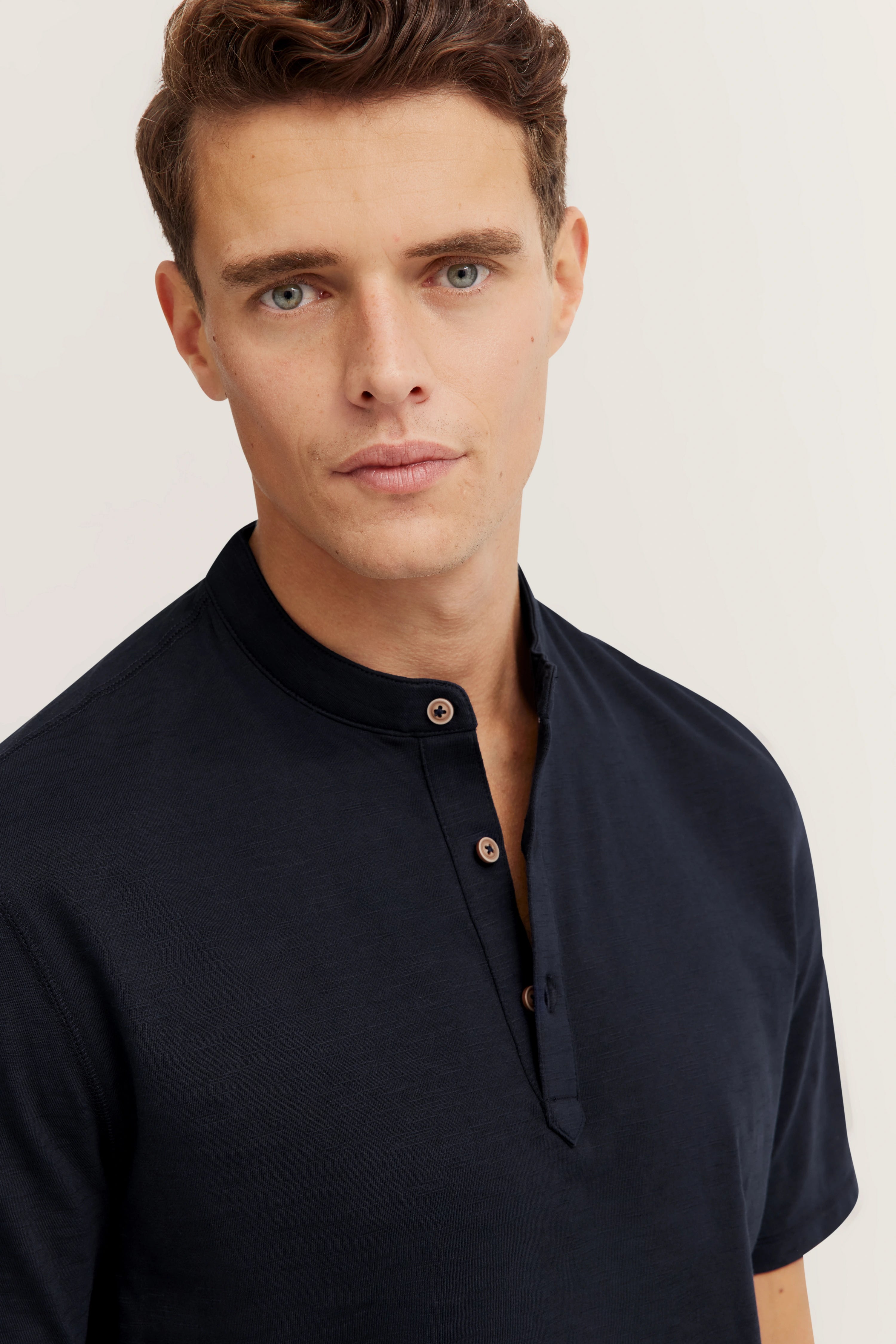 Model in navy Henley shirt by bugatti, bust shot, relaxed pose.