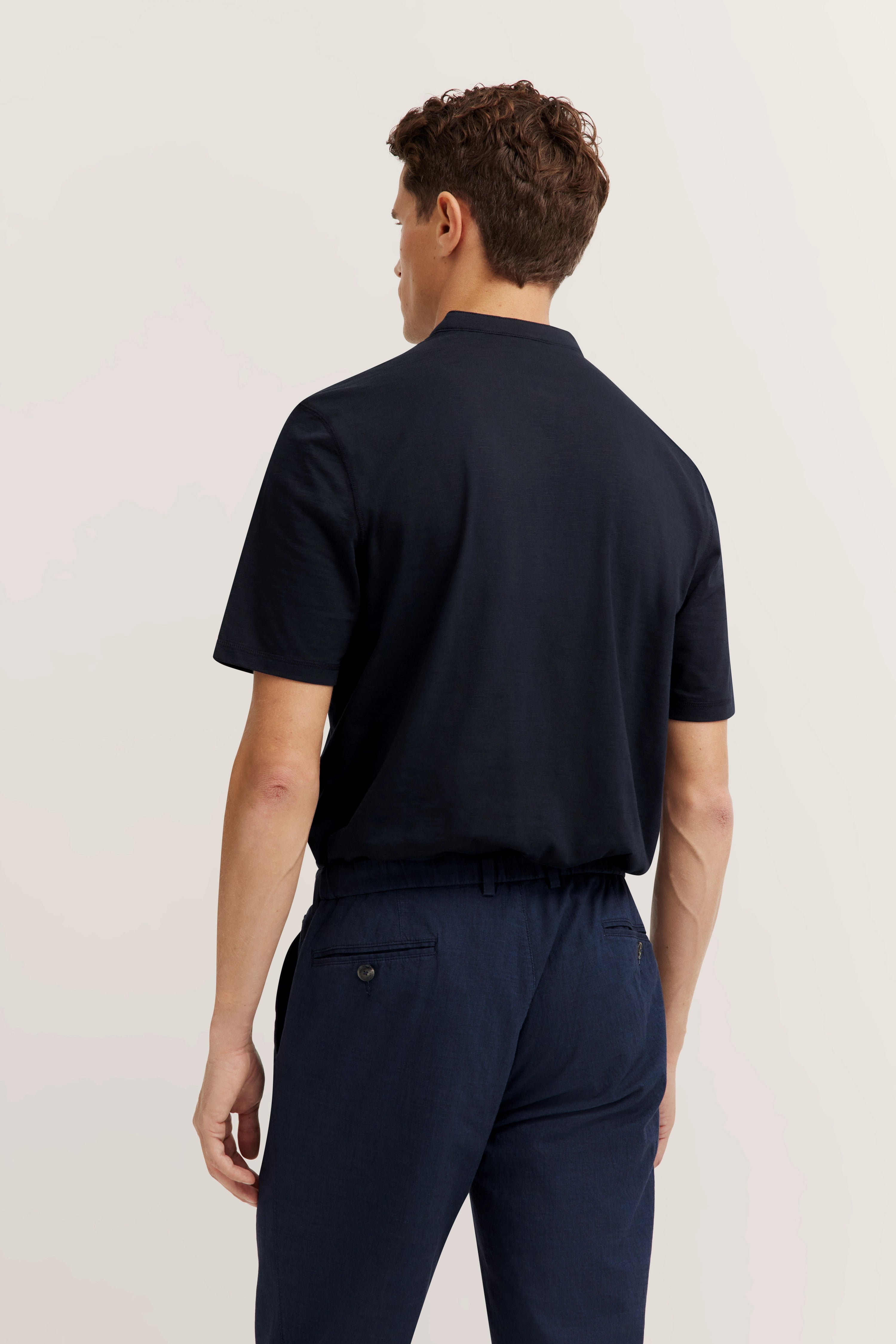 Navy polo shirt and pants by bugatti, model from behind.