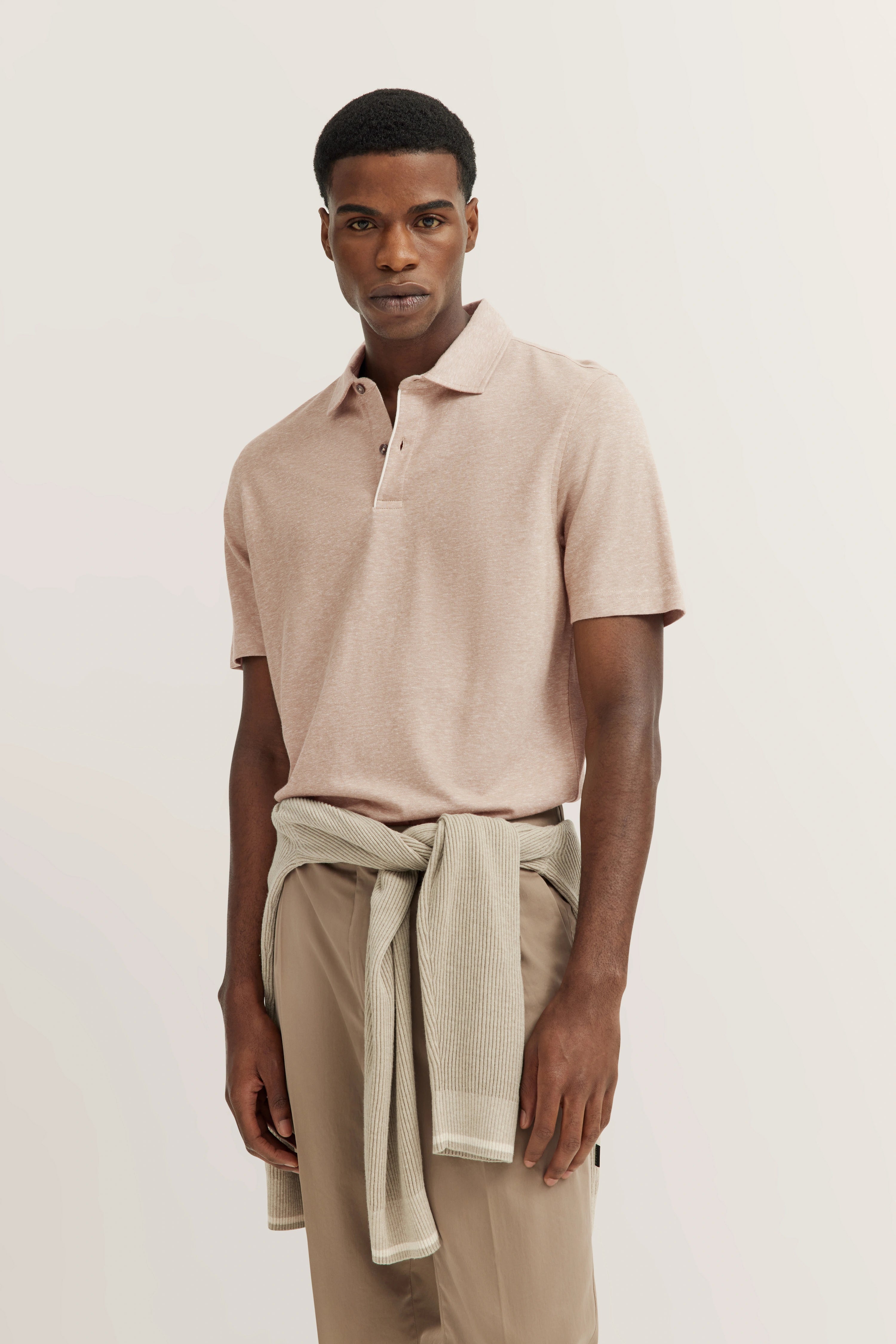 bugatti model: Beige polo, beige pants, sweater at hips, relaxed pose, exuding timeless elegance and Italian flair.
