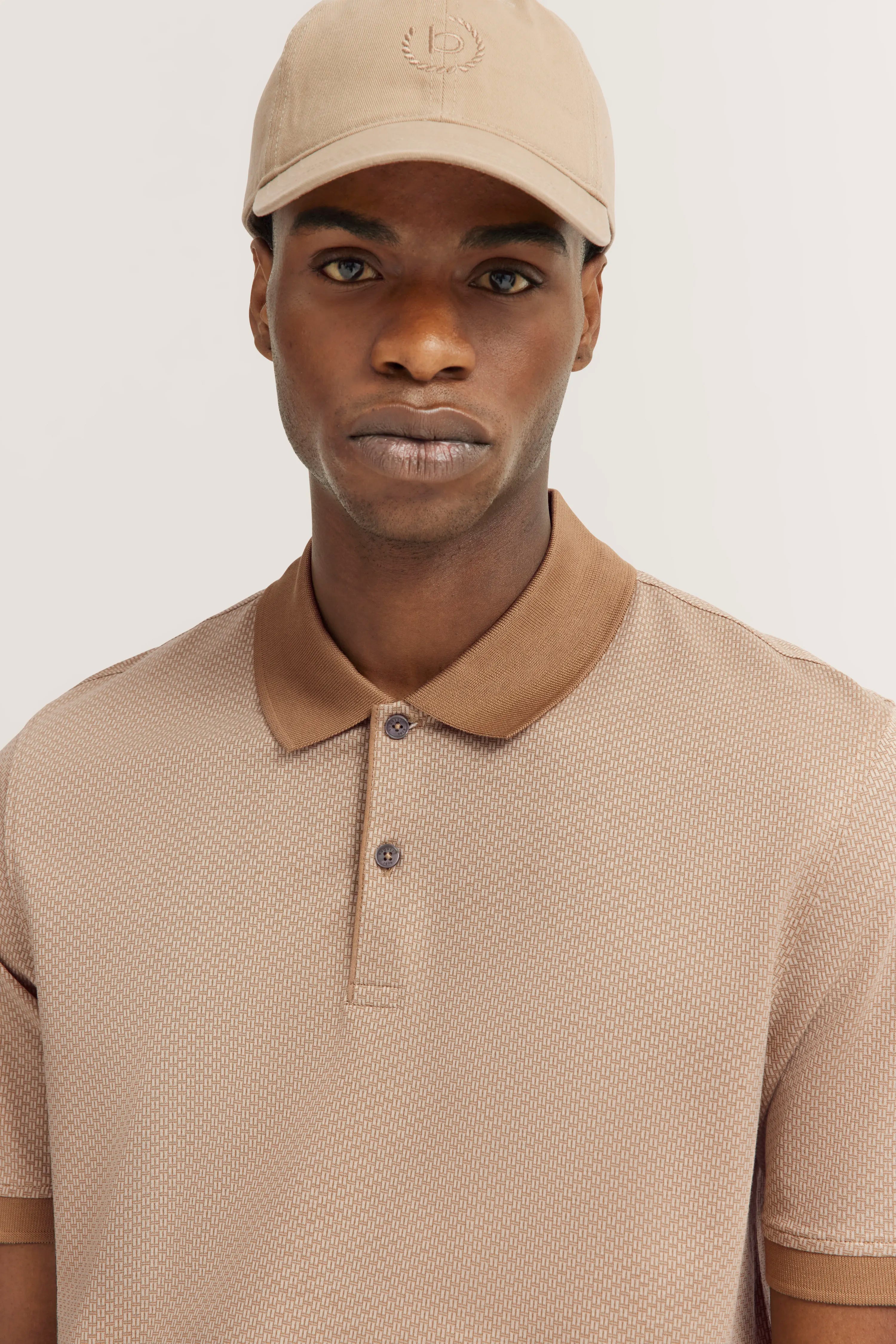 bugatti model image, man in beige polo and cap, relaxed pose, timeless style.