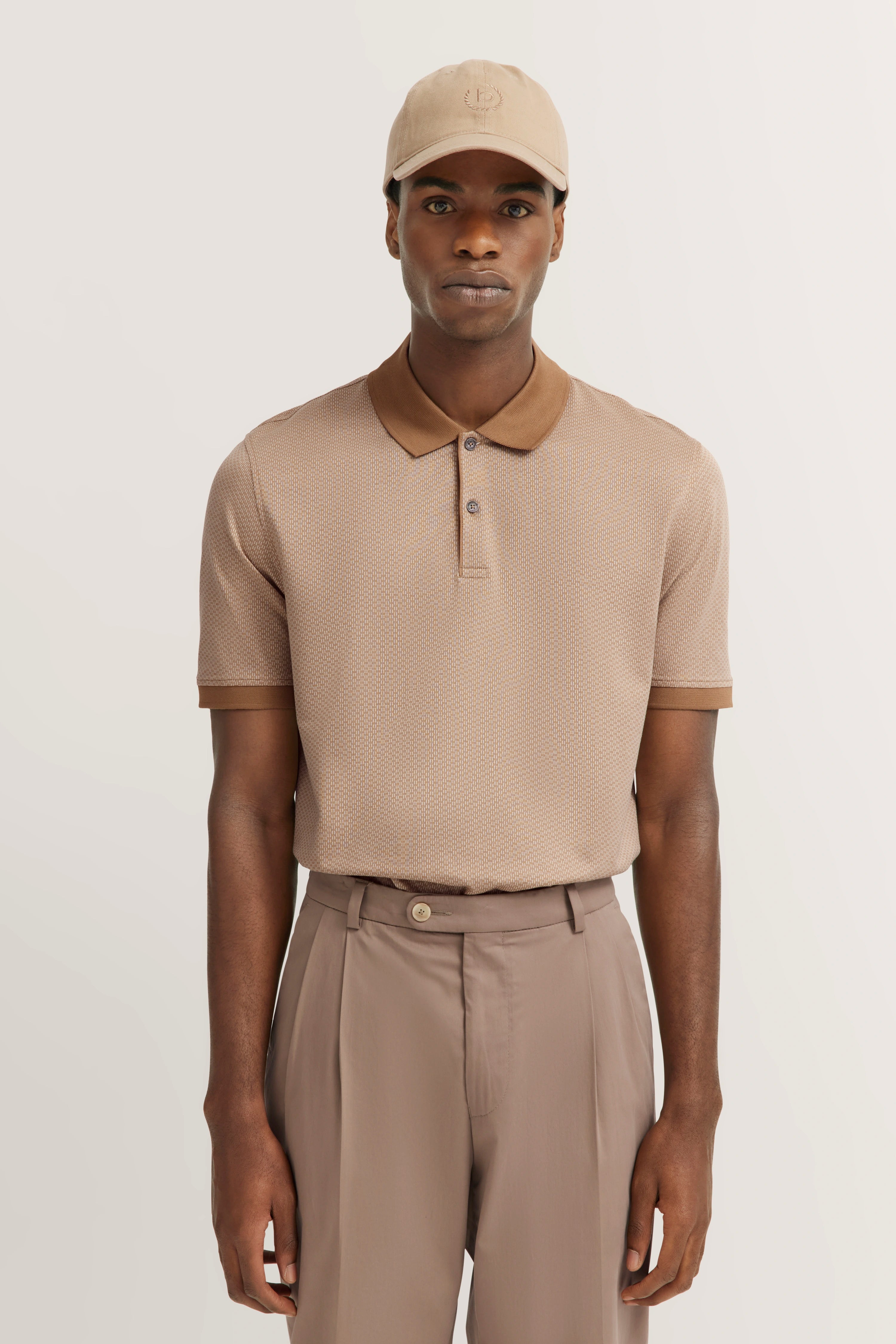 Man in beige polo and trousers with matching cap, exuding bugatti's refined Italian-inspired elegance.
