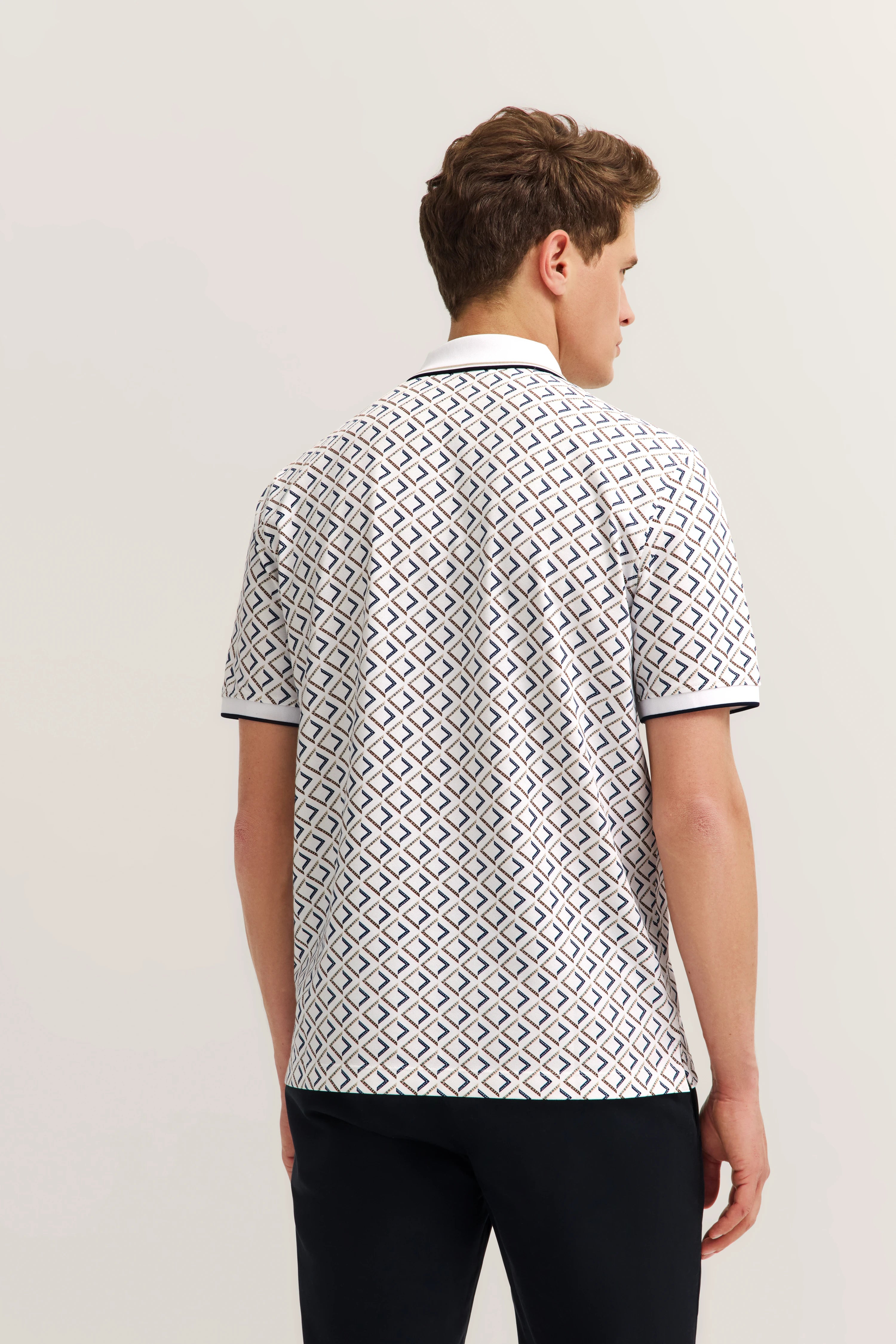 Rückansicht eines Modelbilds mit gemustertem, weiß-blauem bugatti Polohemd und schwarzen Hosen.