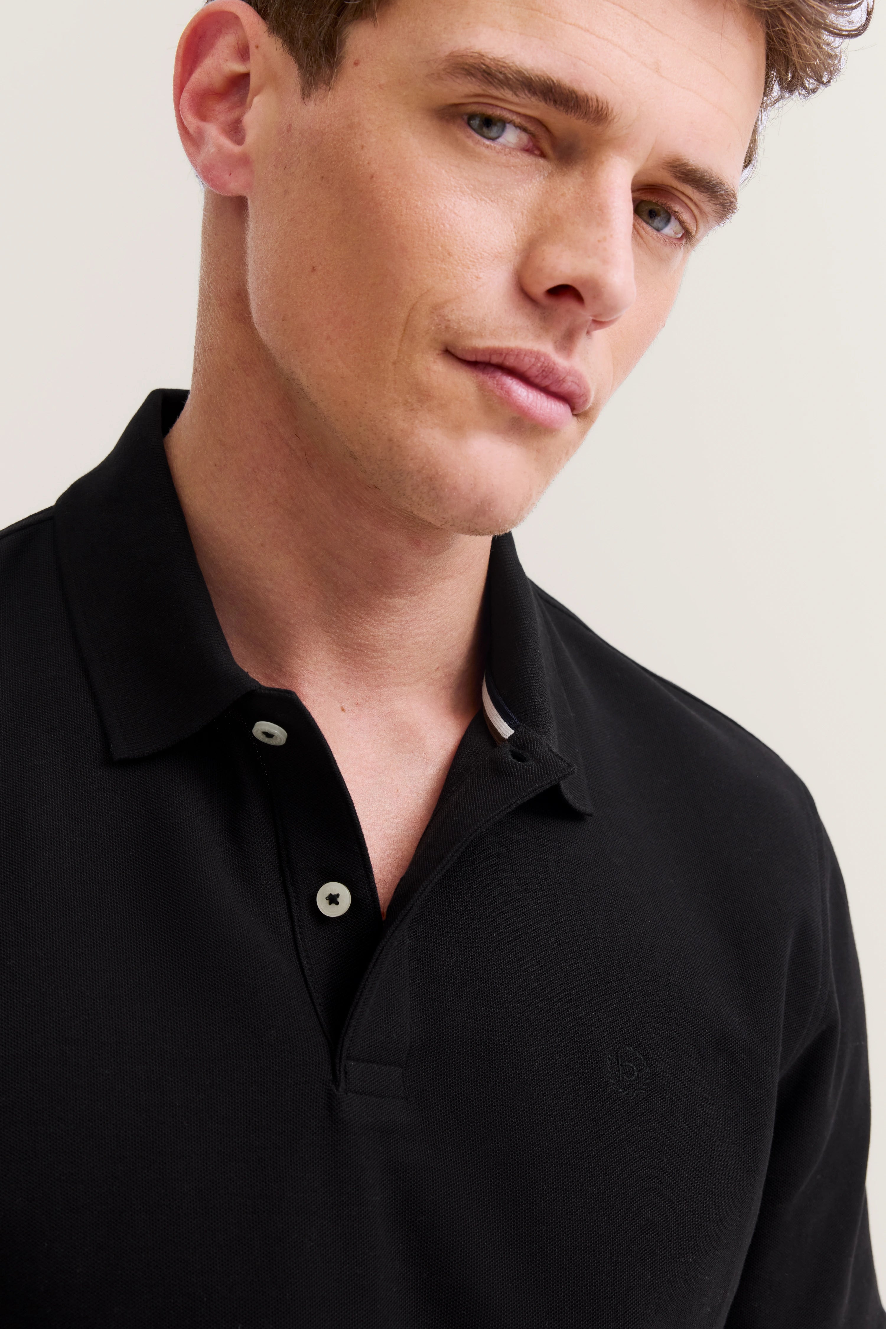 Schwarzes bugatti Polohemd, Modelbild, entspannter Gesichtsausdruck.