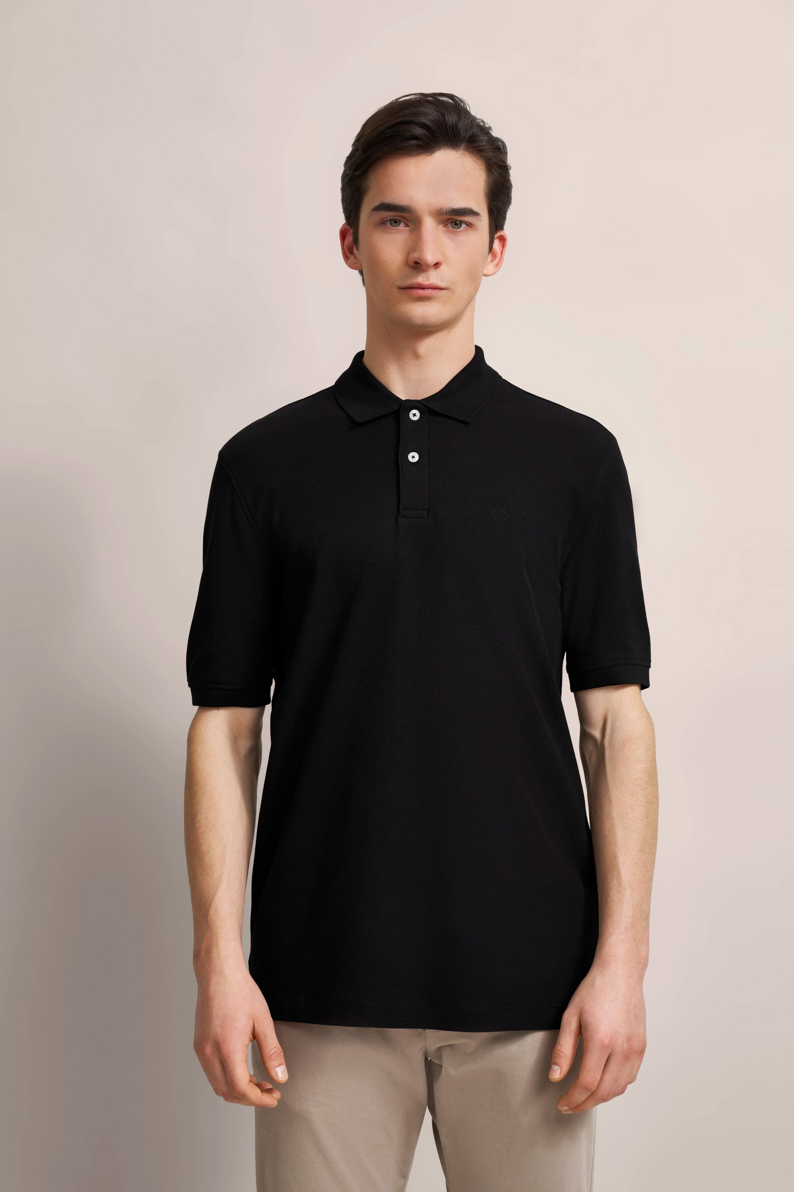 Black polo shirt by bugatti, model shot, front view, casual pose, beige pants.