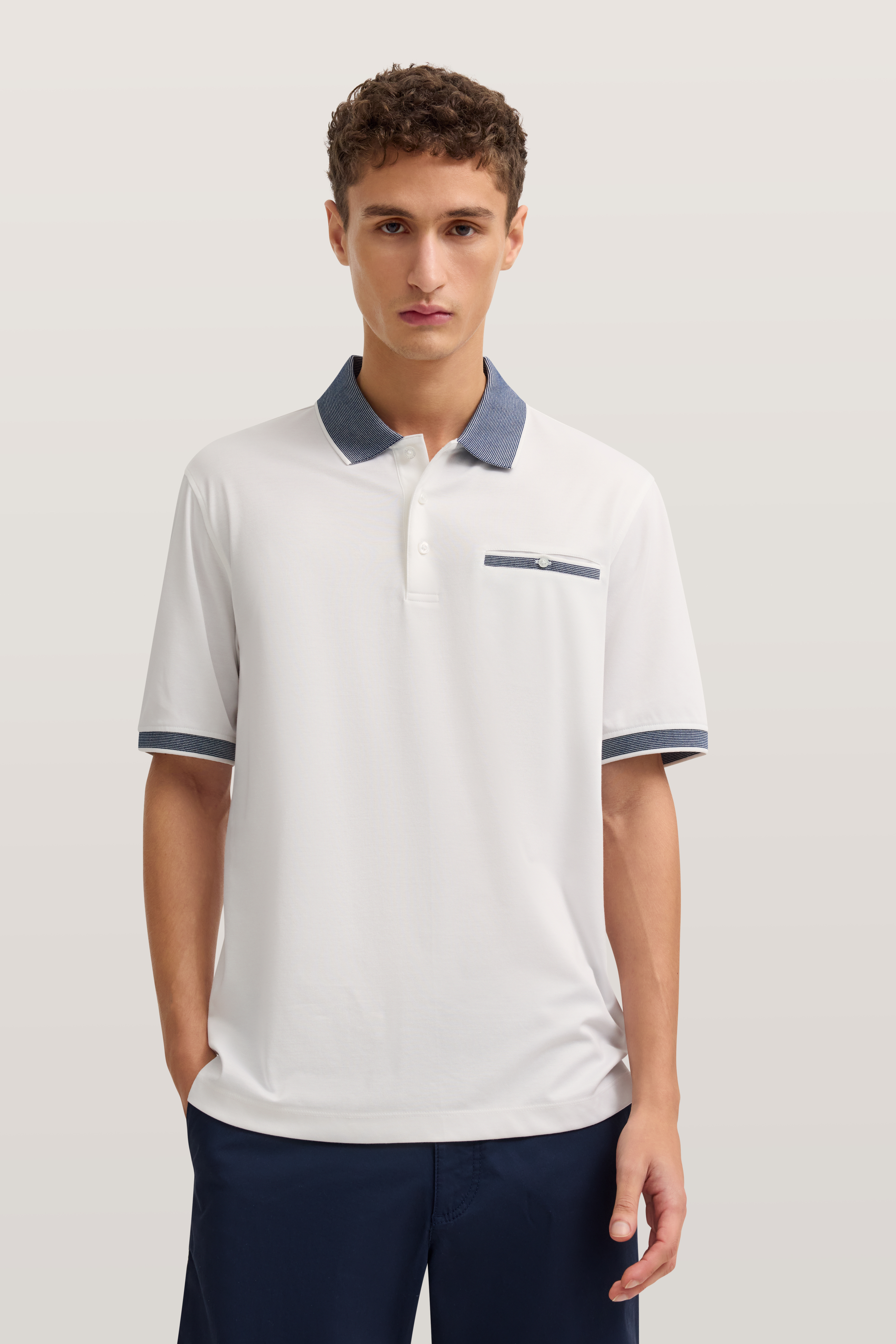 Weiße Polo-Shirt von bugatti mit blauem Kragen und Details, Model frontal stehend.