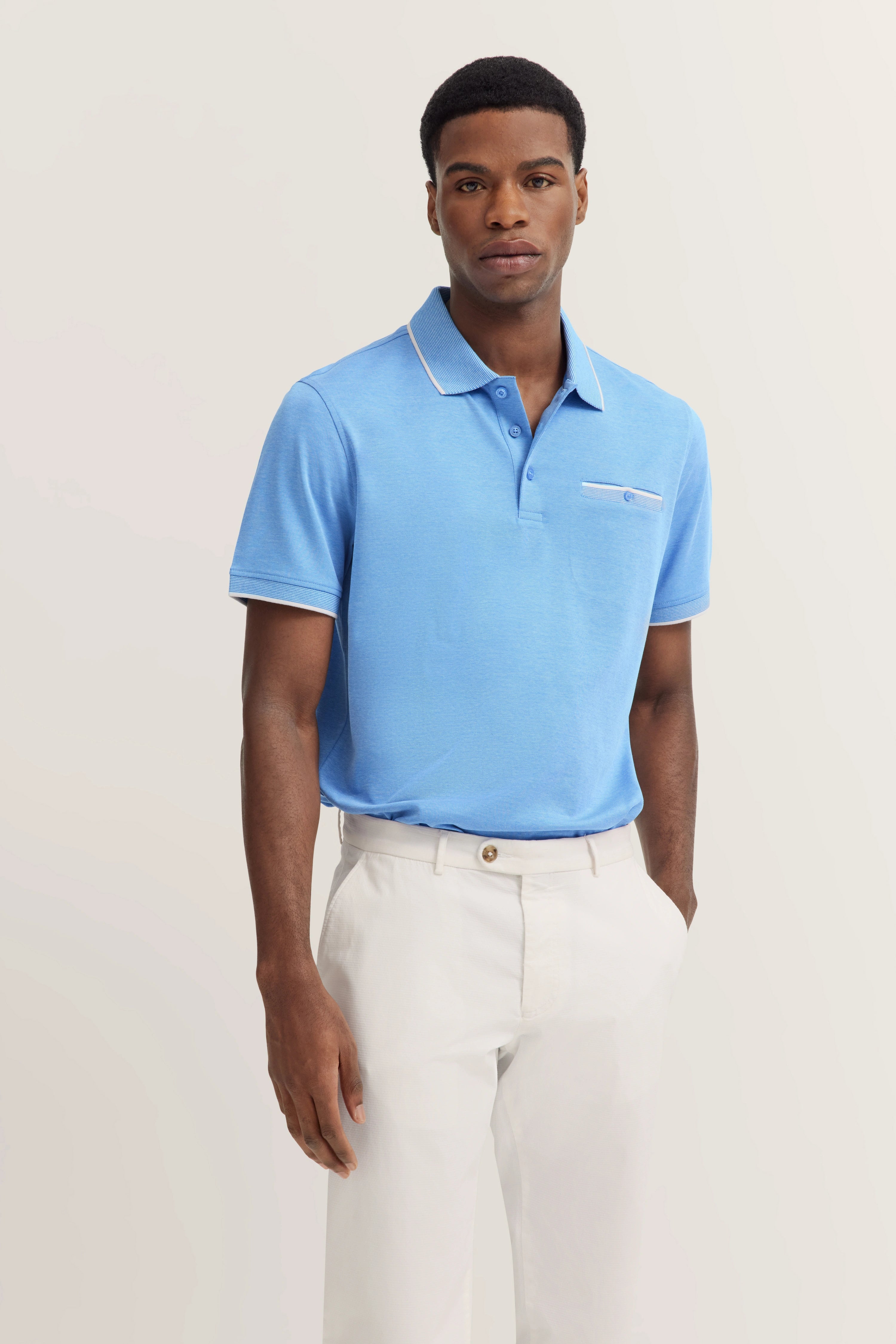 Blue polo shirt with white pants, standing model, relaxed pose.