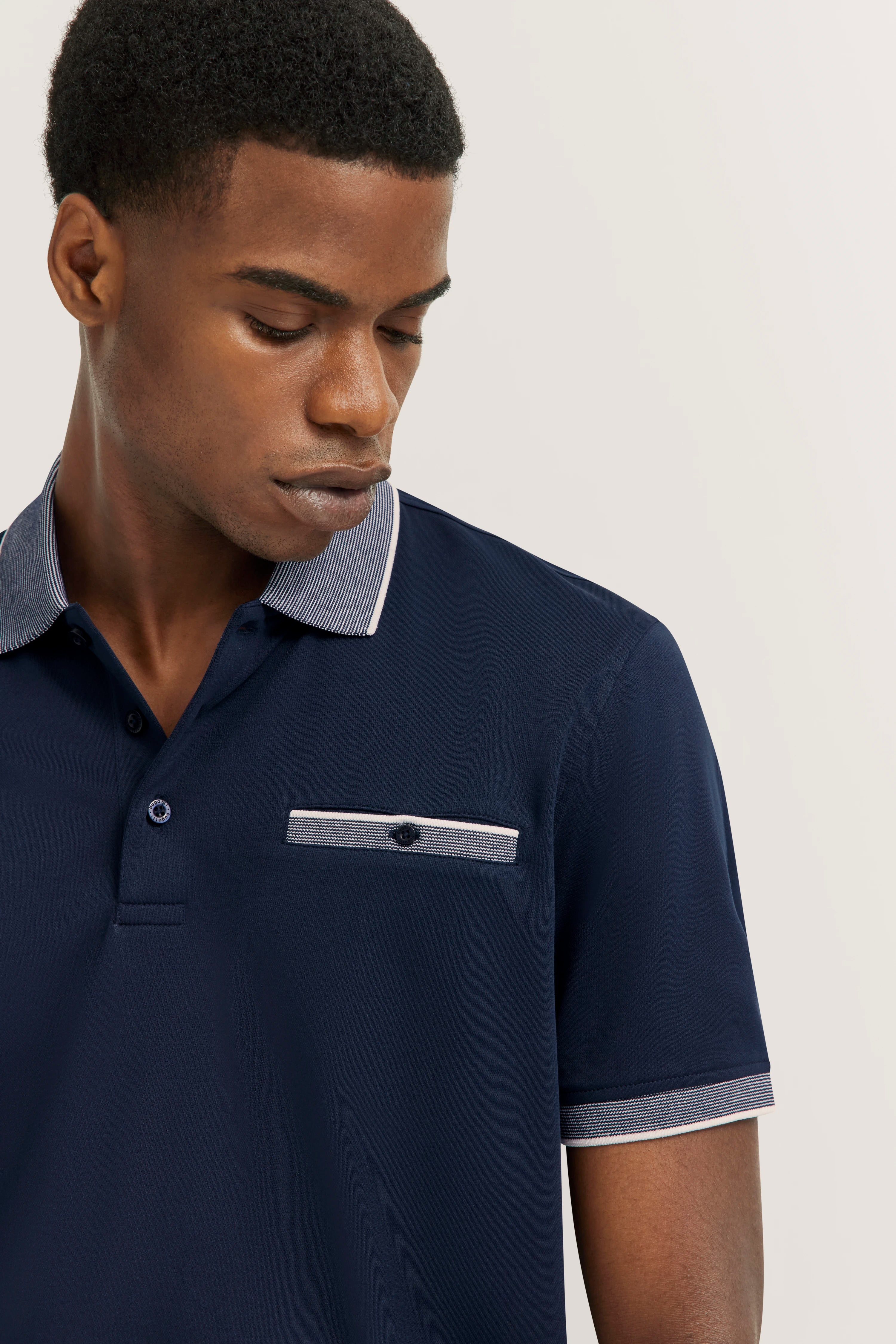 Dark blue bugatti polo with striped collar, model in relaxed pose.