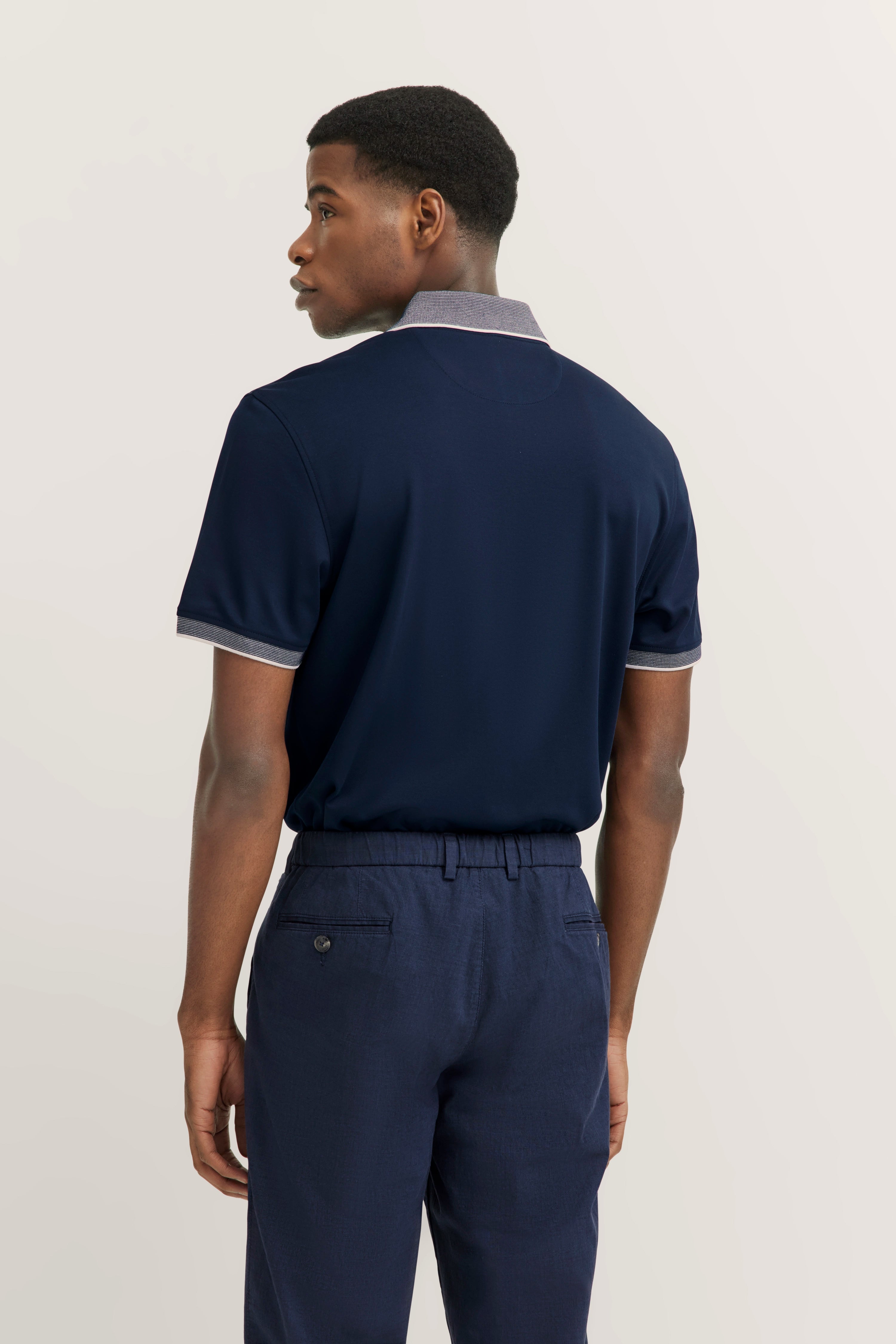 bugatti outfit: navy polo, navy trousers, model from behind.