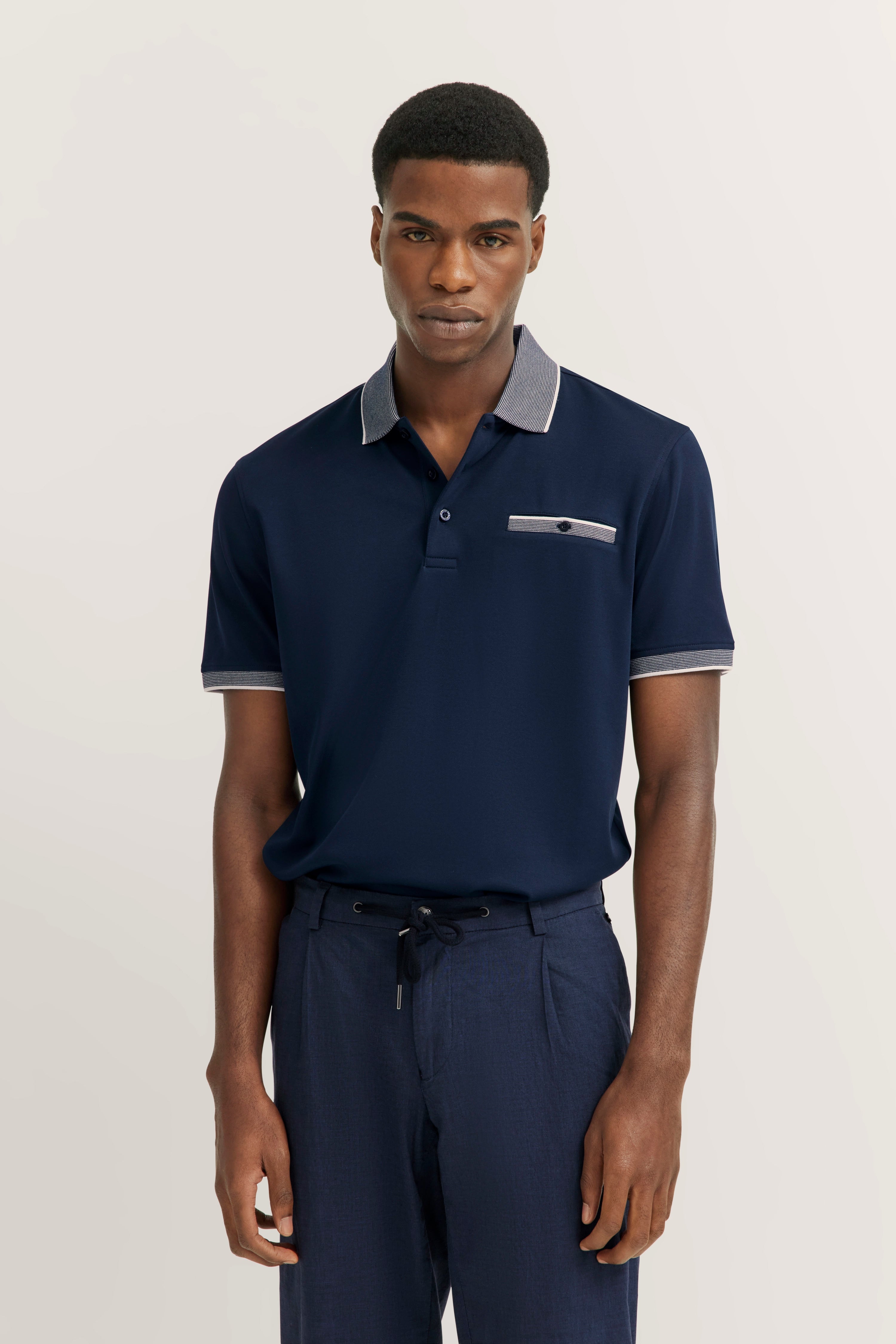Navy polo and pants, model in relaxed pose, bugatti style and elegance.